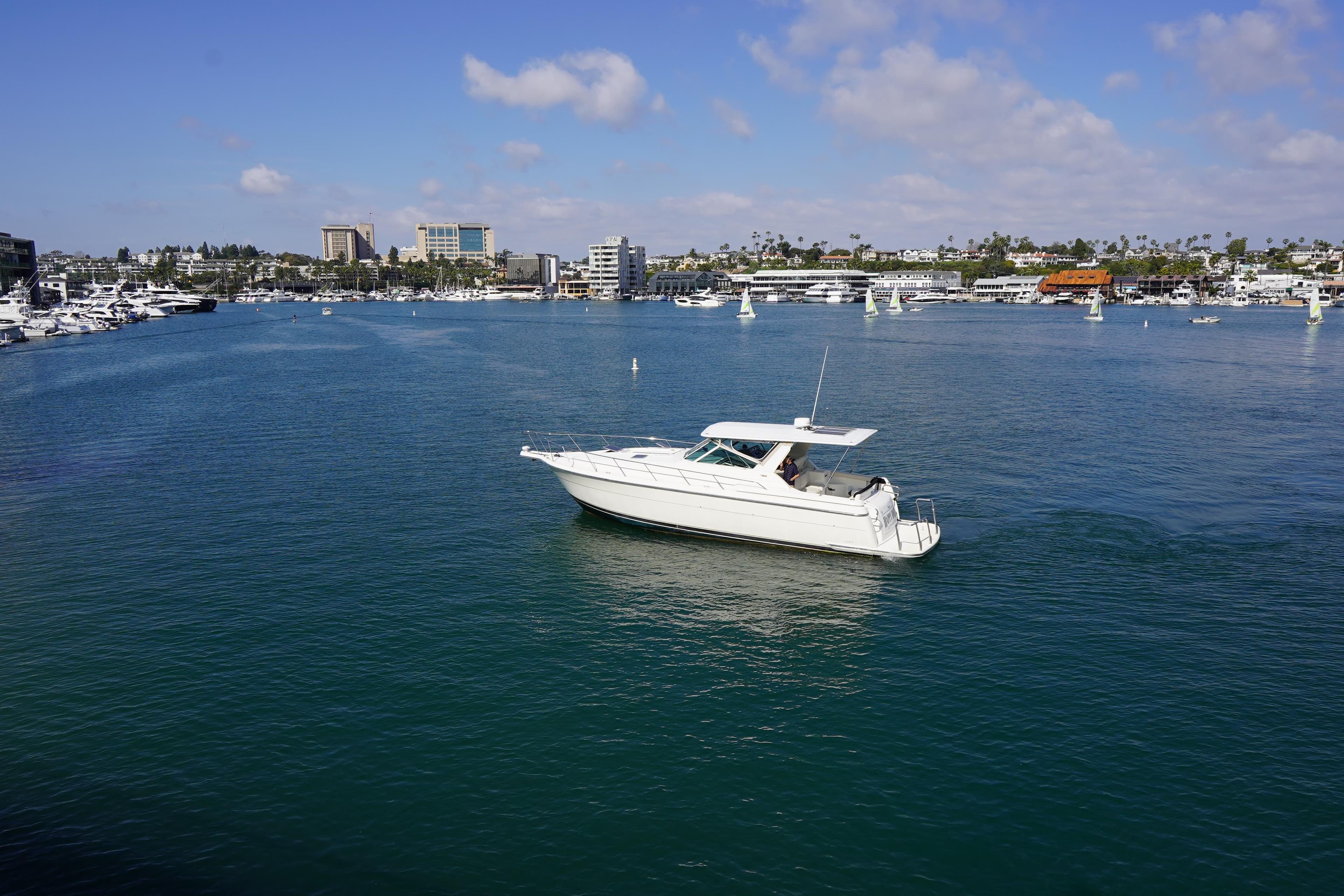 1994 Tiara Yachts 4000 Express cruising in a scenic harbor with city skyline backdrop.