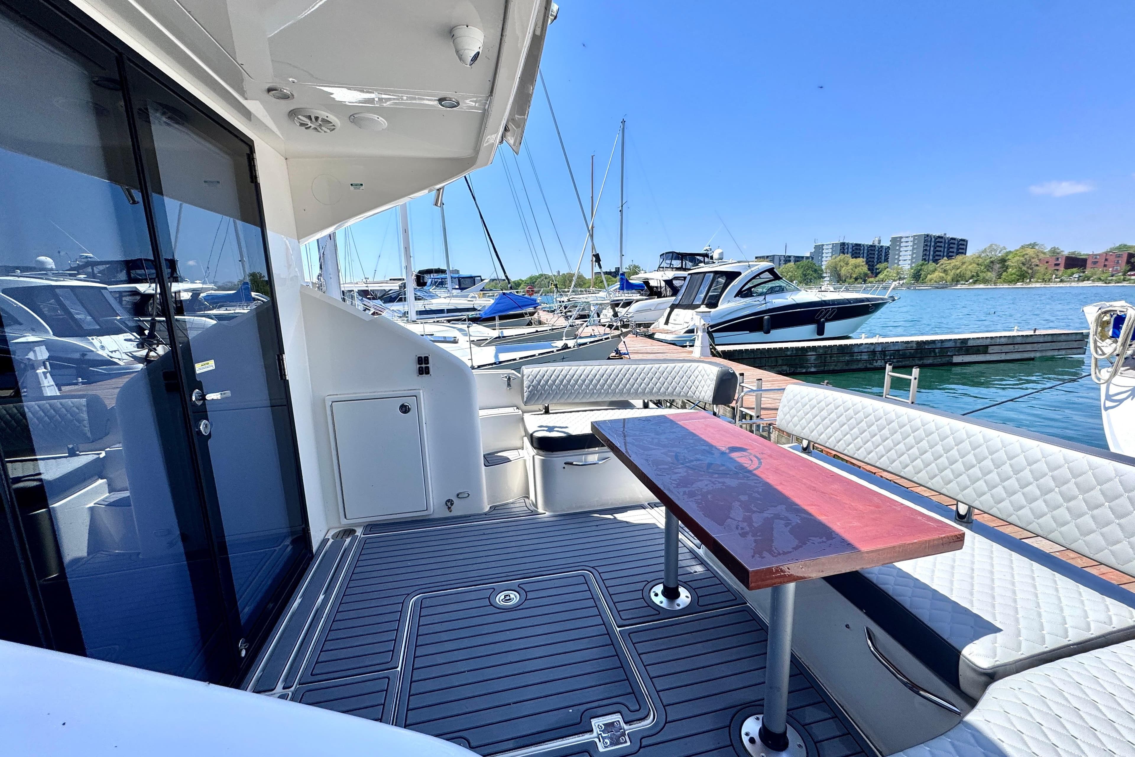 Outdoor seating area on a 2015 Carver C37 yacht, docked at a marina.