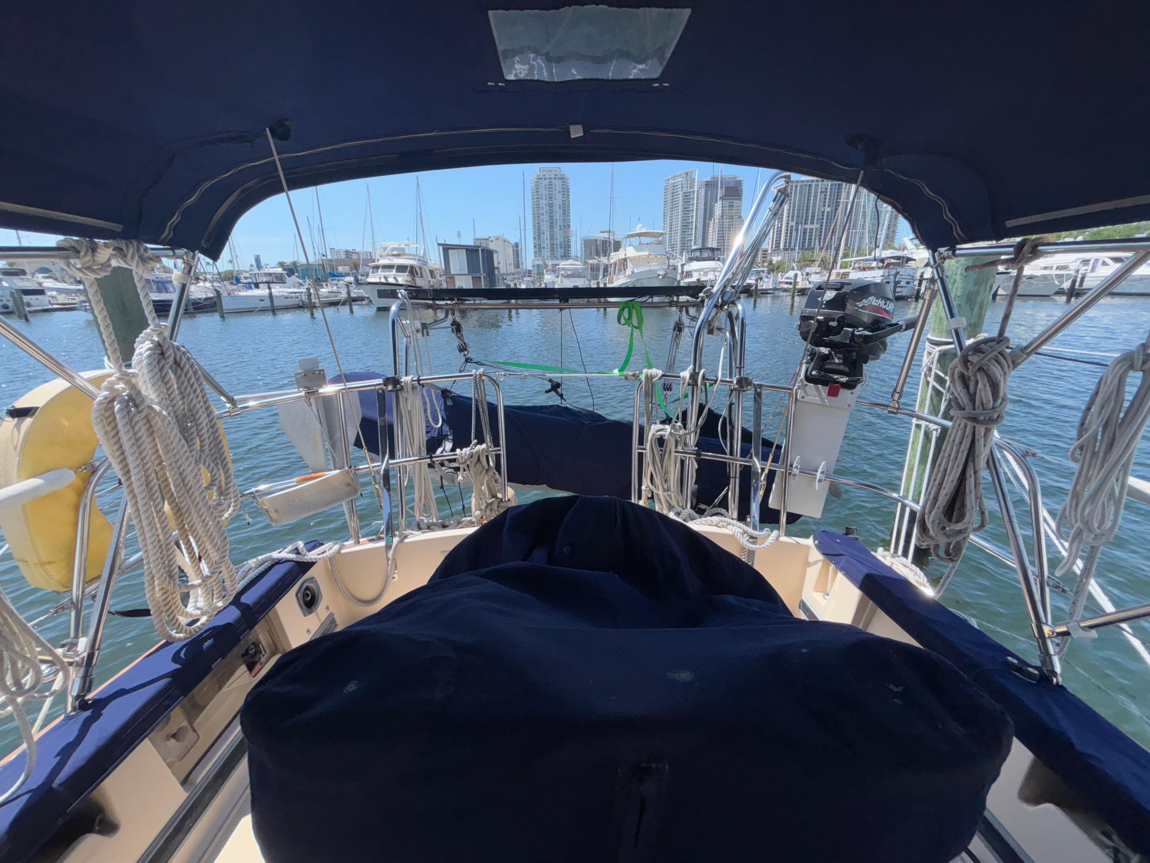 Cockpit view of 1995 Island Packet 37 sailboat docked in marina with city skyline.