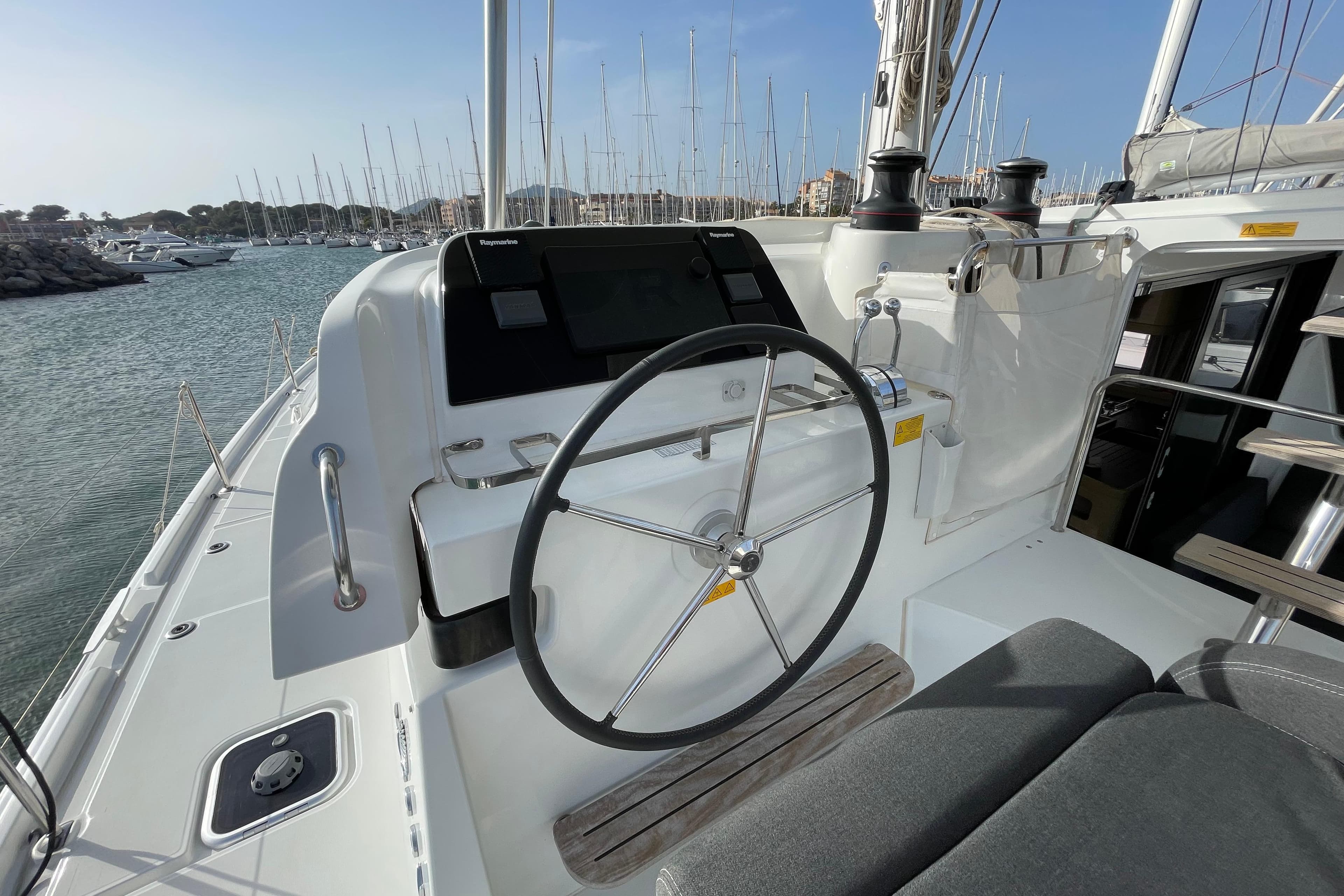 2023 Lagoon 42 yacht helm with steering wheel and navigation system in marina.