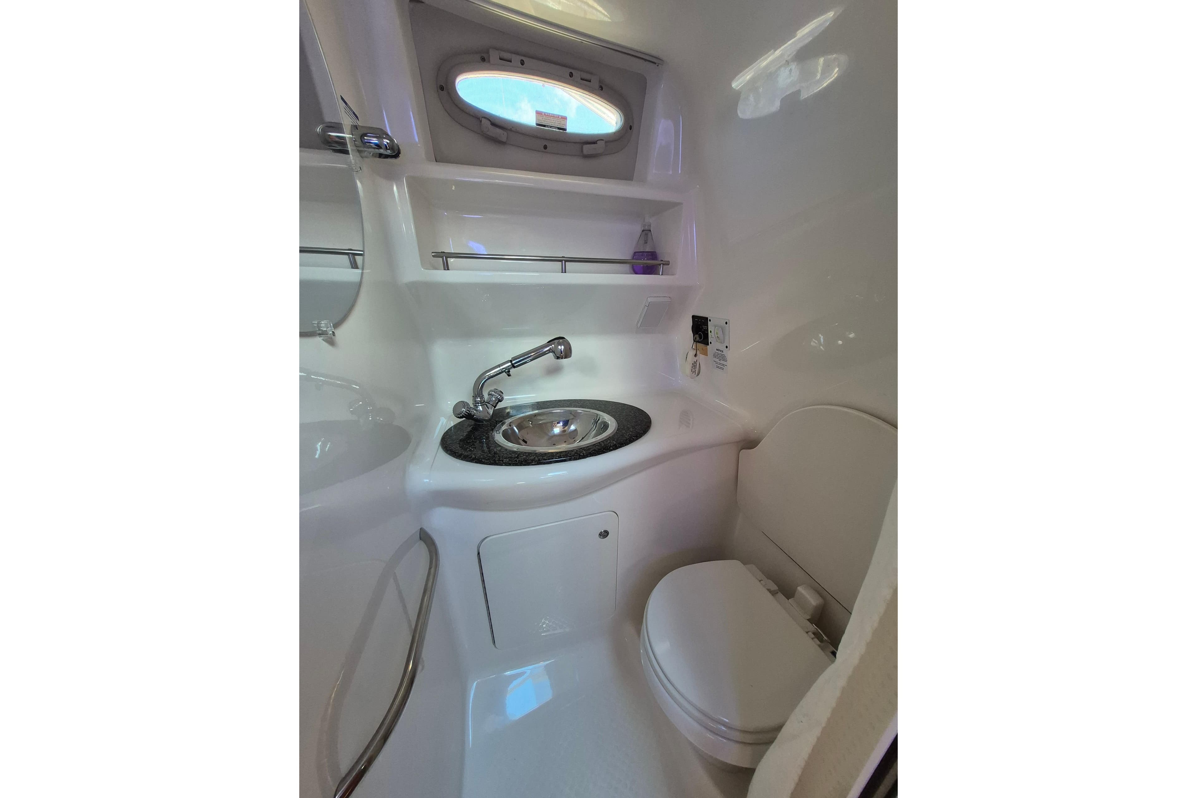 2008 Chaparral Signature 280 boat bathroom with sink, toilet, and porthole window.