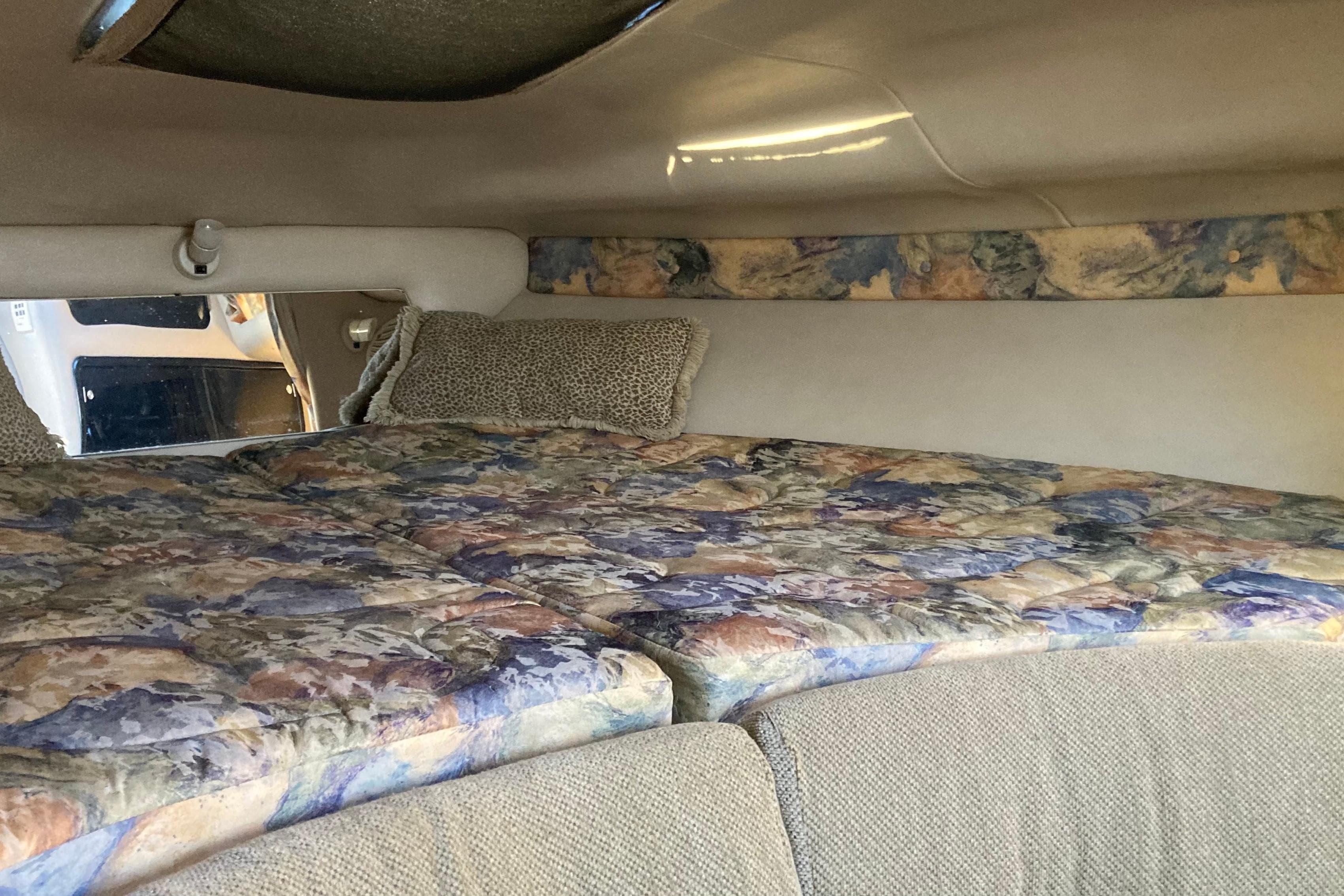 Interior cabin of 1999 Chaparral Signature 29 with floral-patterned bedding and cozy decor.