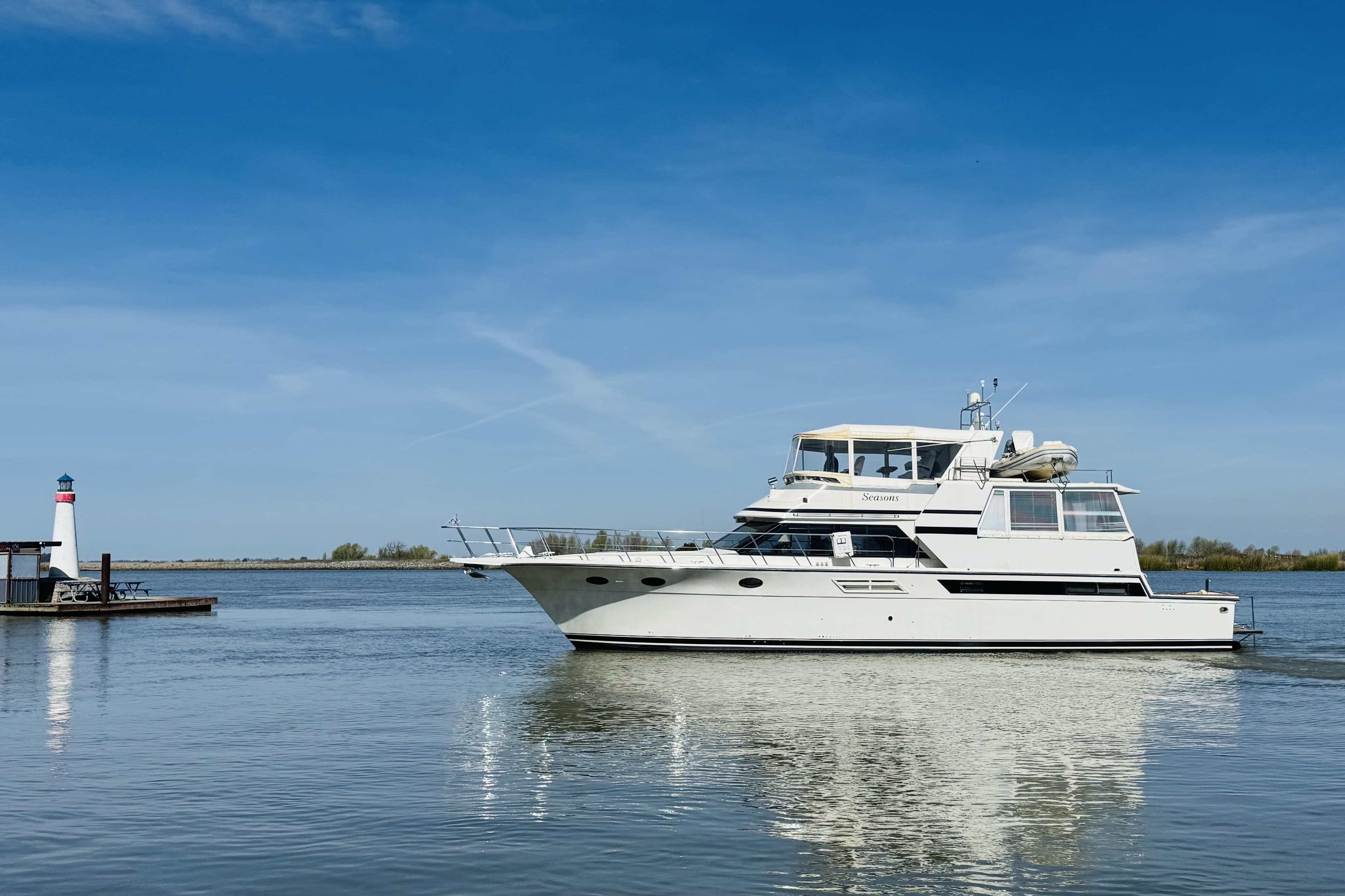 1991 Californian 55 Cockpit Motor Yacht on calm water near a small lighthouse.