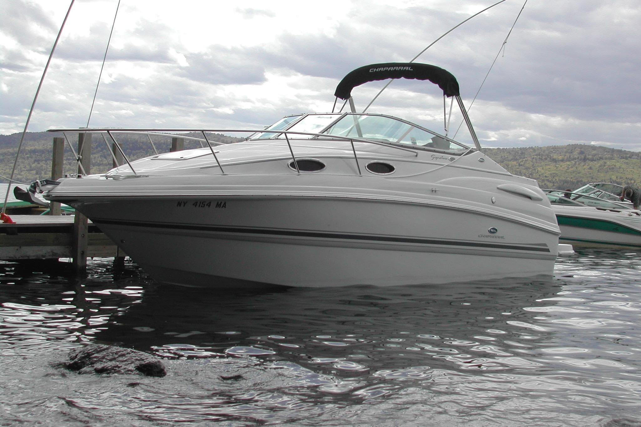 2005 Chaparral Signature 260 boat docked on a calm lake under cloudy skies.