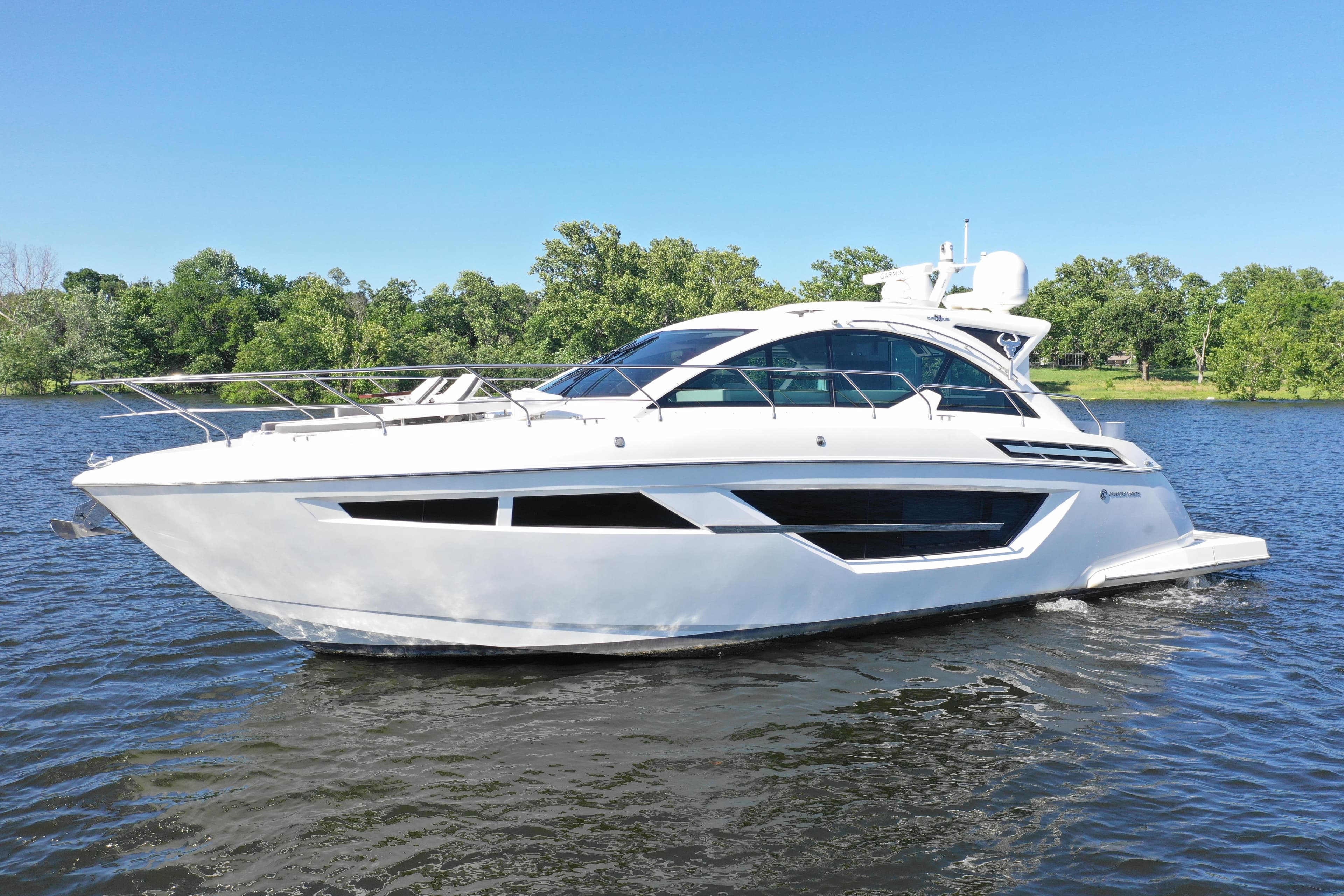 2019 Cruisers Yachts 50 Cantius on a serene lake with lush green shoreline.