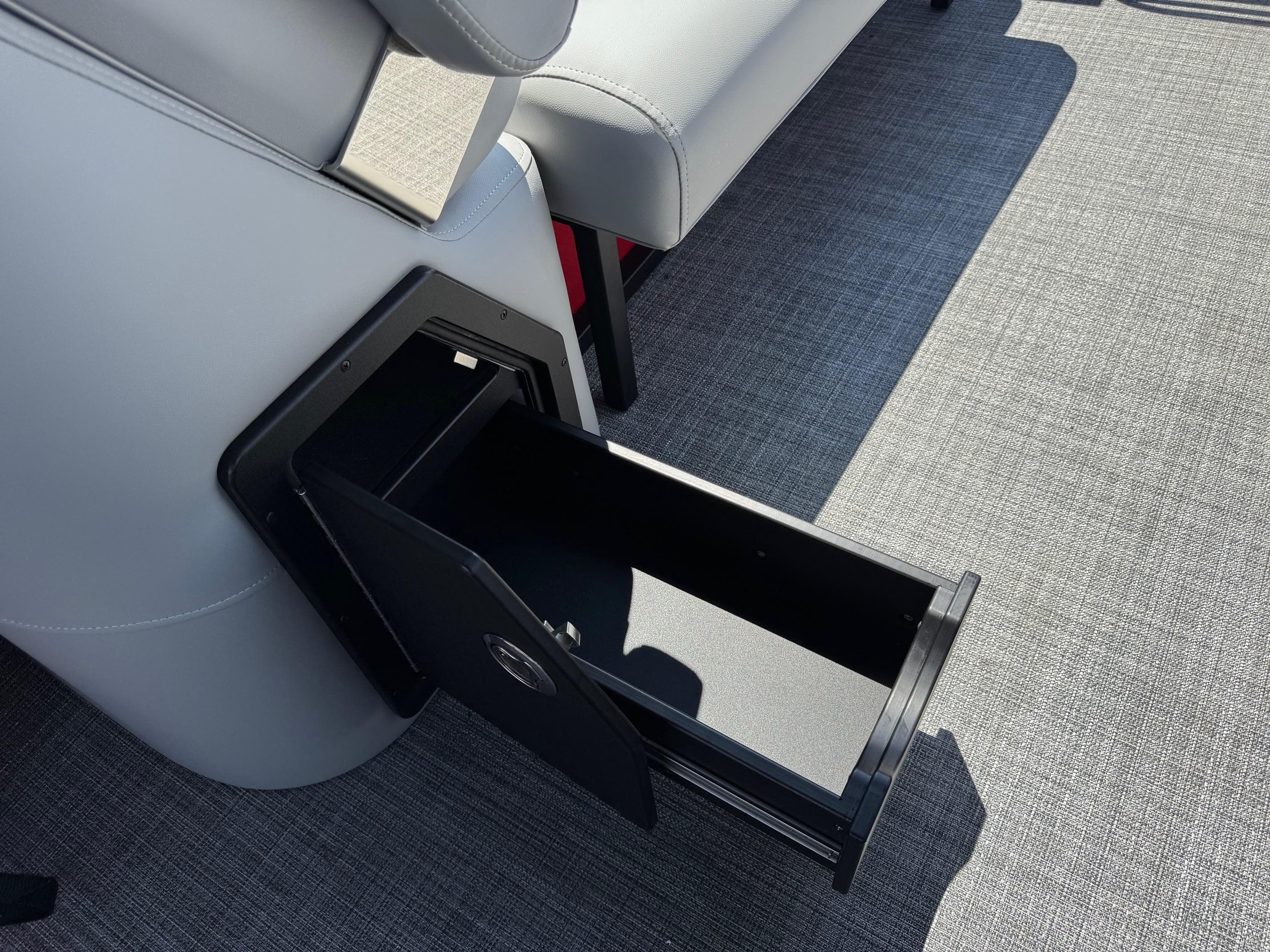 Open storage compartment on 2026 JC SportToon 24 TT DSL boat, featuring sleek design and gray upholstery.
