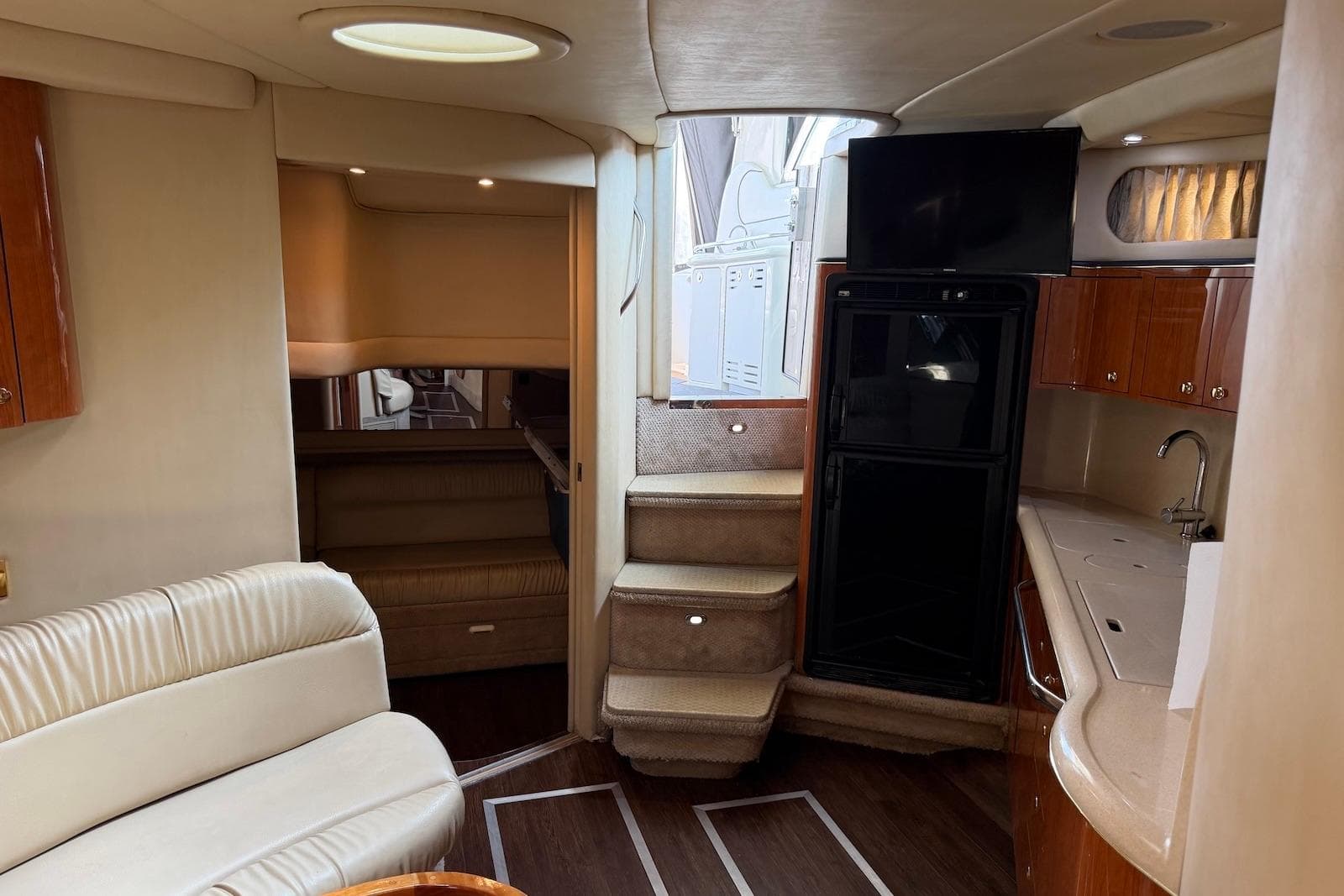 Interior of 2000 Sea Ray 410 Sundancer yacht with seating, kitchenette, and stairs.