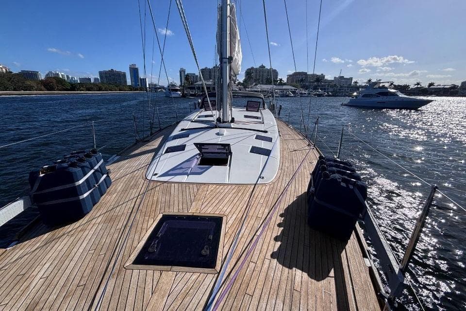 2015 Beneteau Sense 55 sailboat on water, wooden deck, city skyline in background.