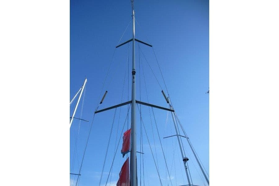 Tall mast of a 2013 Jeanneau 379 sailboat against a clear blue sky.