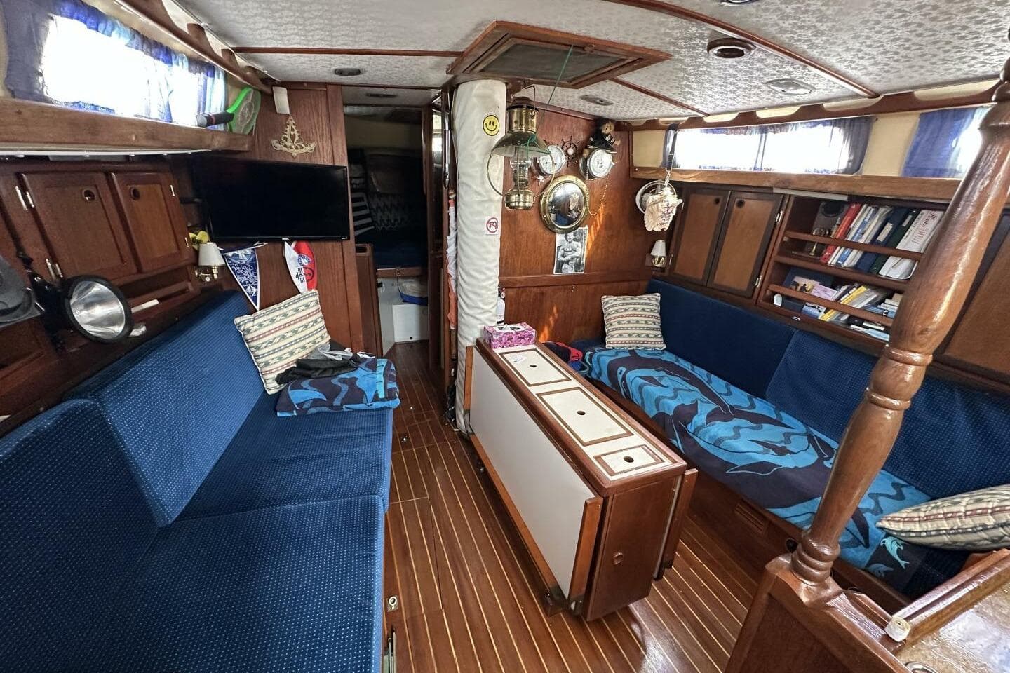 Cozy 1979 Hughes 3910 yacht interior with blue seating, wooden cabinets, and nautical decor.