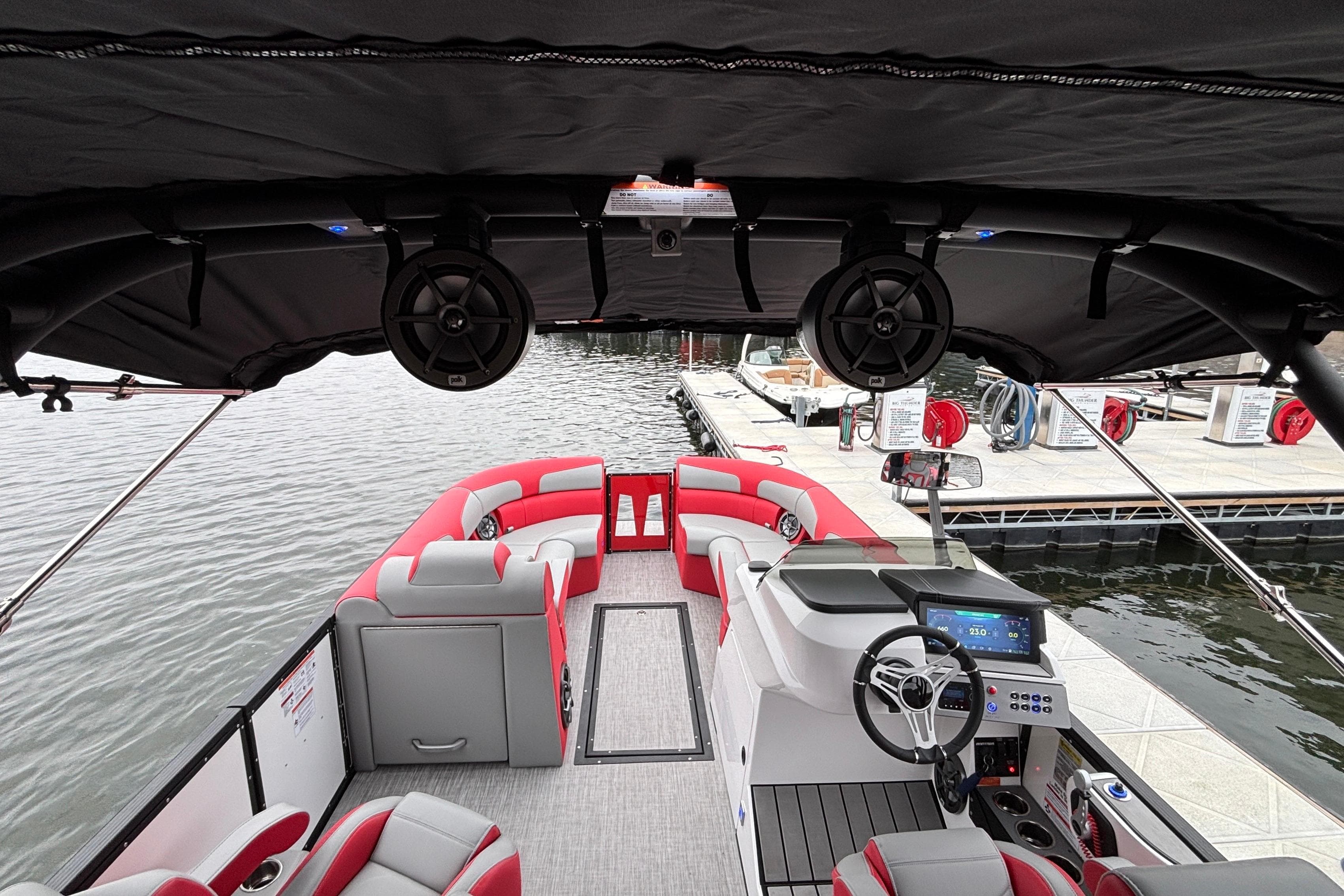 2025 Montara 25 Surf Boss boat interior with red and gray seating, docked by the water.