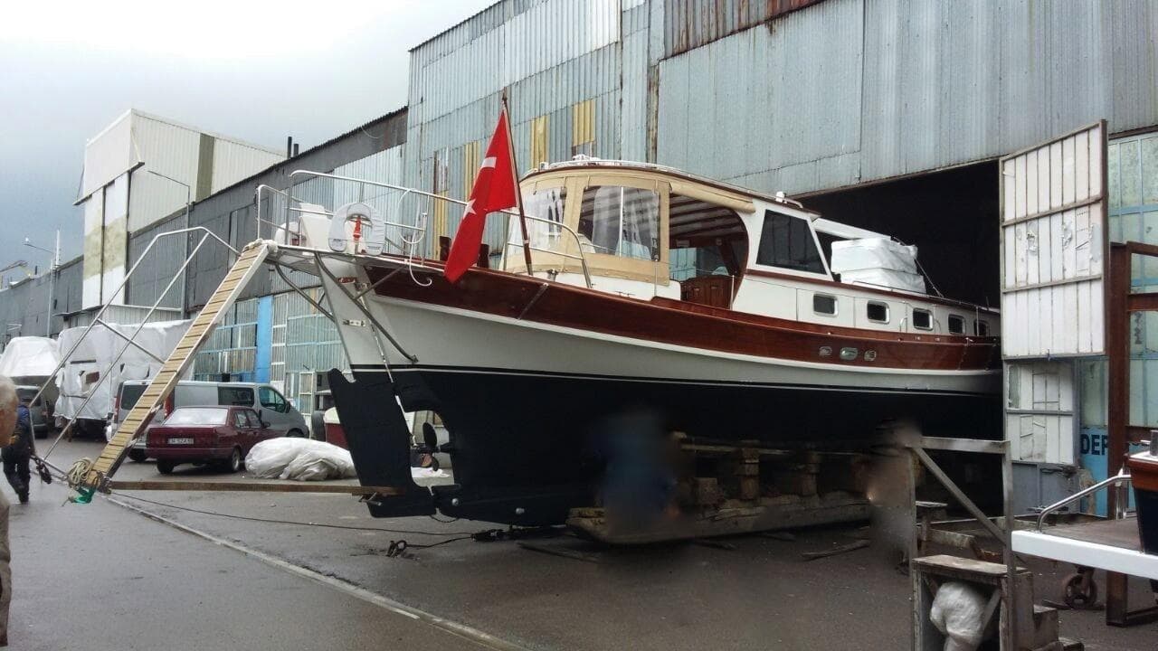 Bodrum Tirhandil 14m boat from 2001 in a shipyard, featuring a red flag.