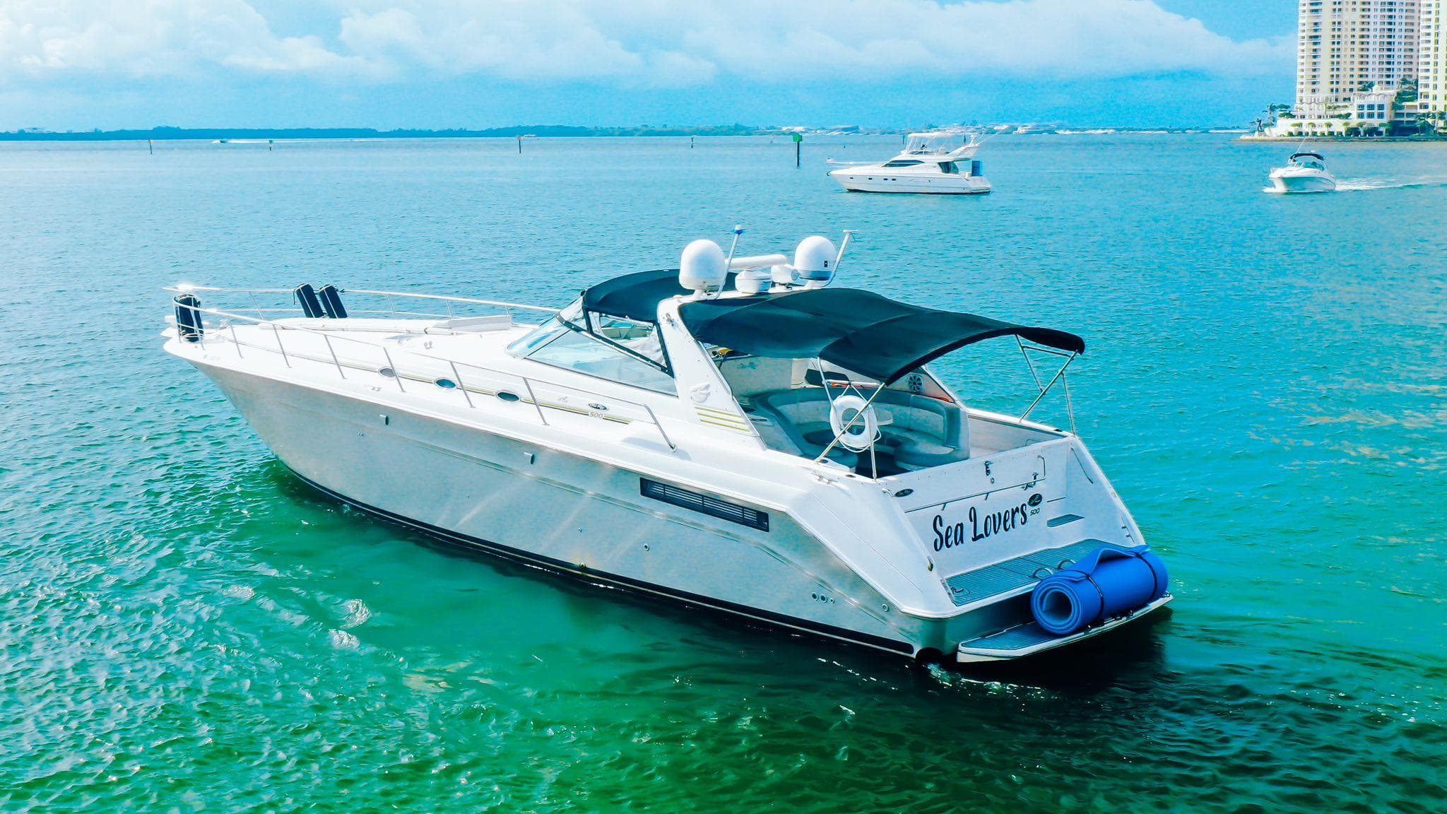 1994 Sea Ray 500 Sundancer yacht on clear blue water, with city skyline in background.
