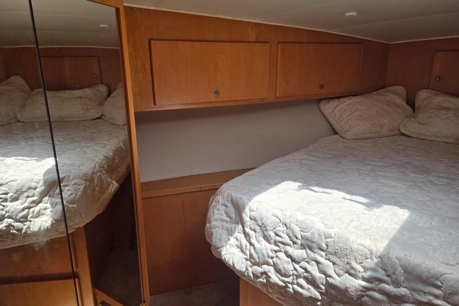 Cozy bedroom in 1994 Navigator 5600 yacht with mirrored closet and wooden cabinets.