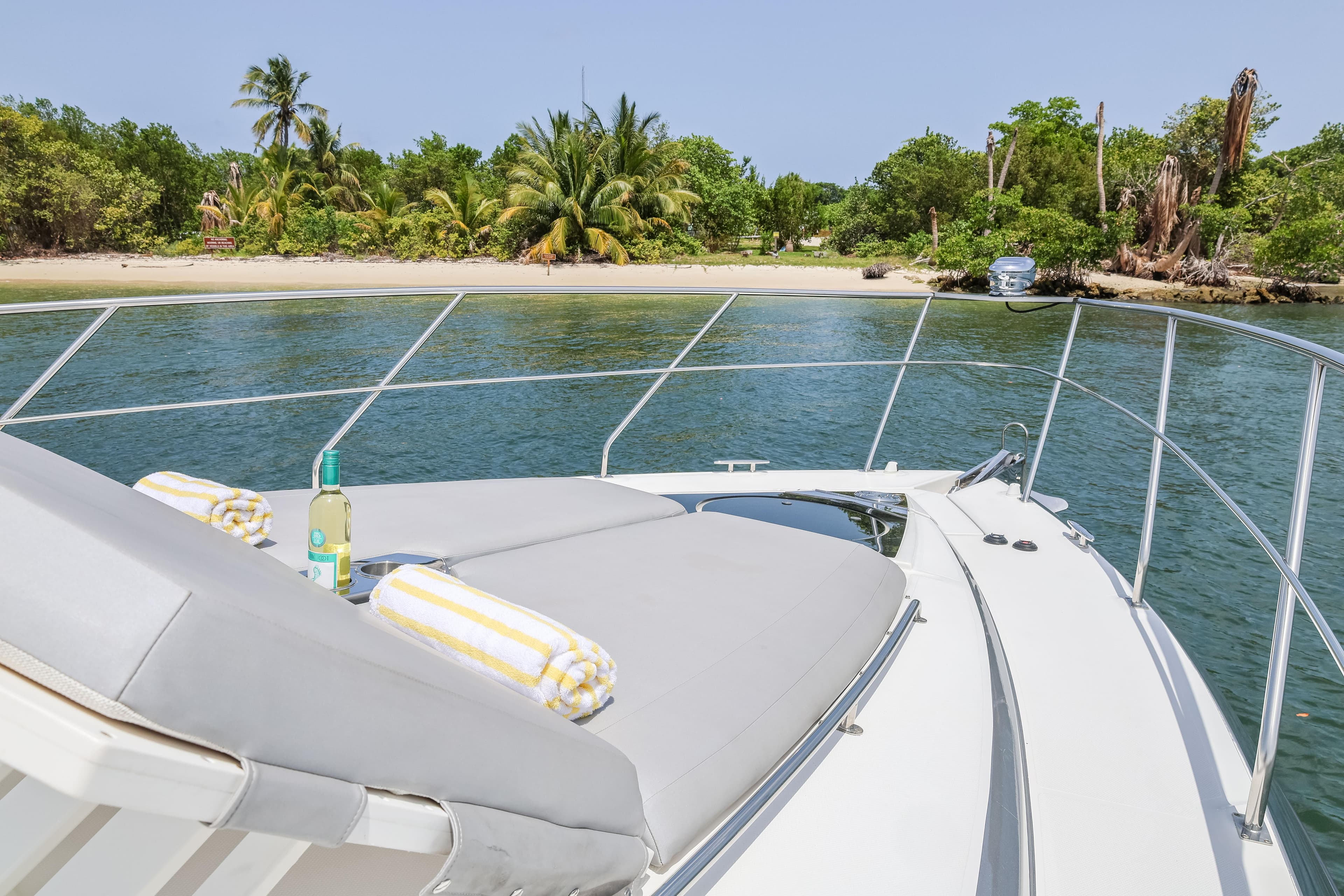 2014 Cruisers Yachts 45 Cantius anchored near tropical beach with sunbathing area.
