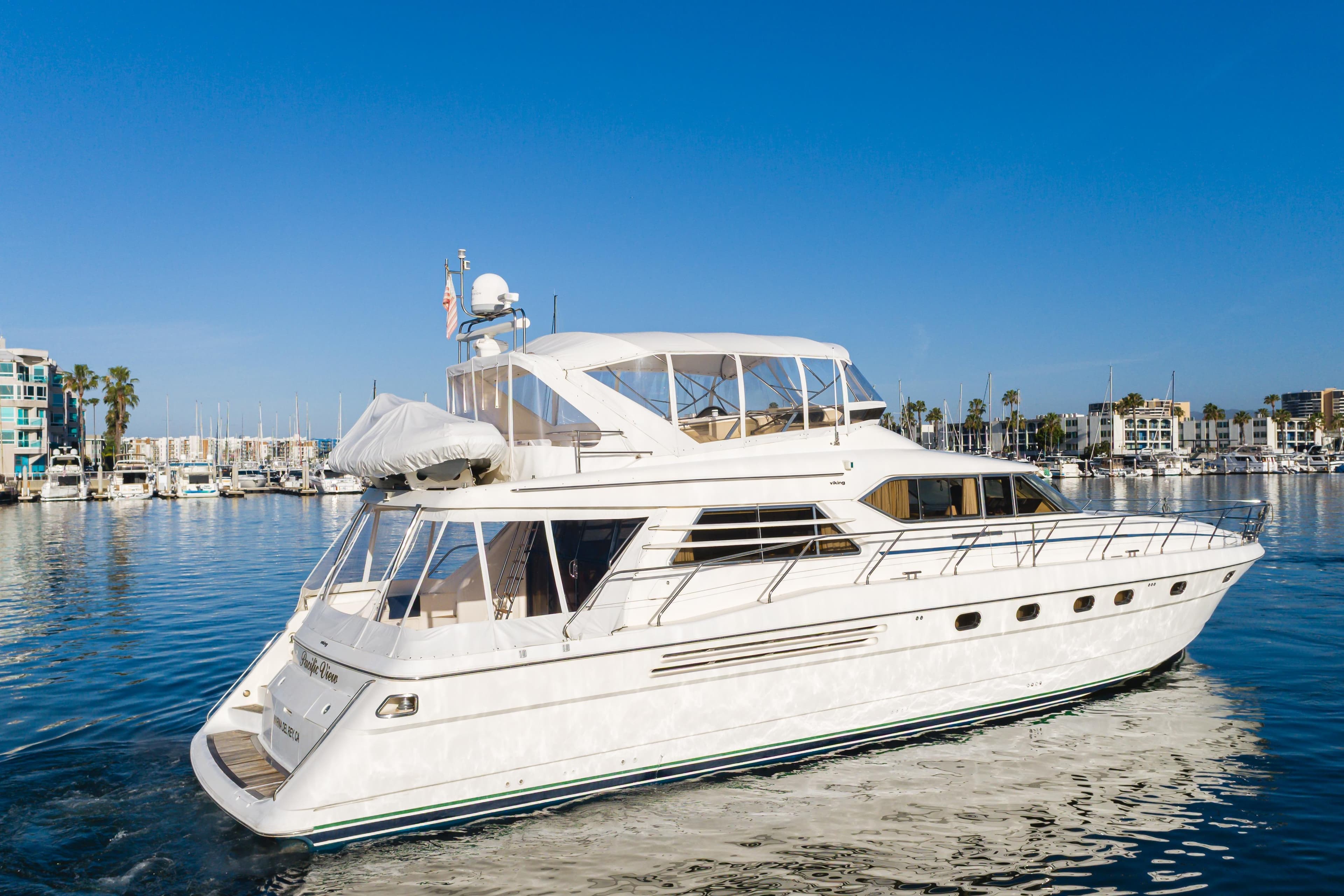 1997 Viking Sport Cruisers 66 Motor Yacht cruising in a marina under clear blue skies.