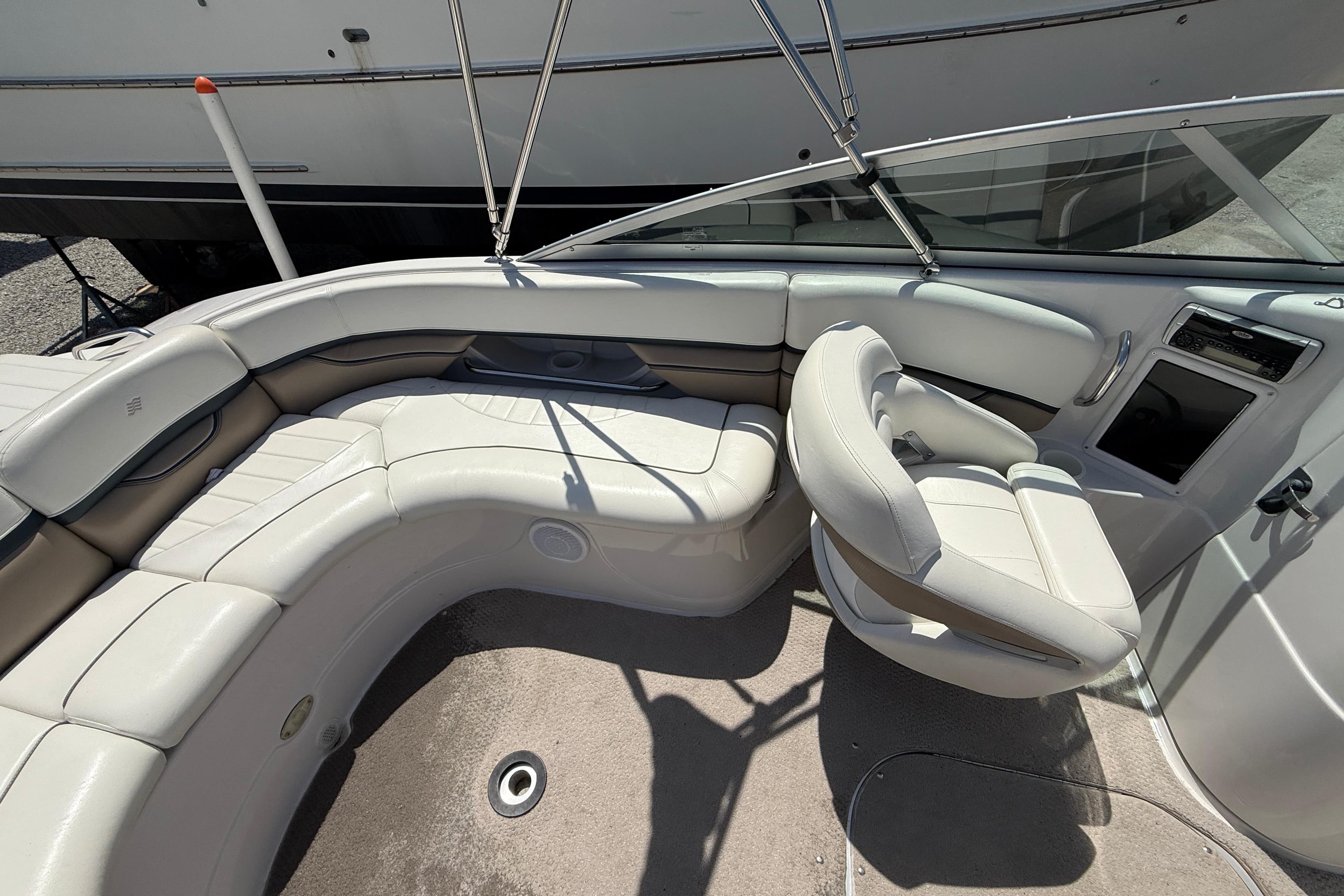 Interior of a 2005 Four Winns 230 Horizon boat with white seating and steering area.
