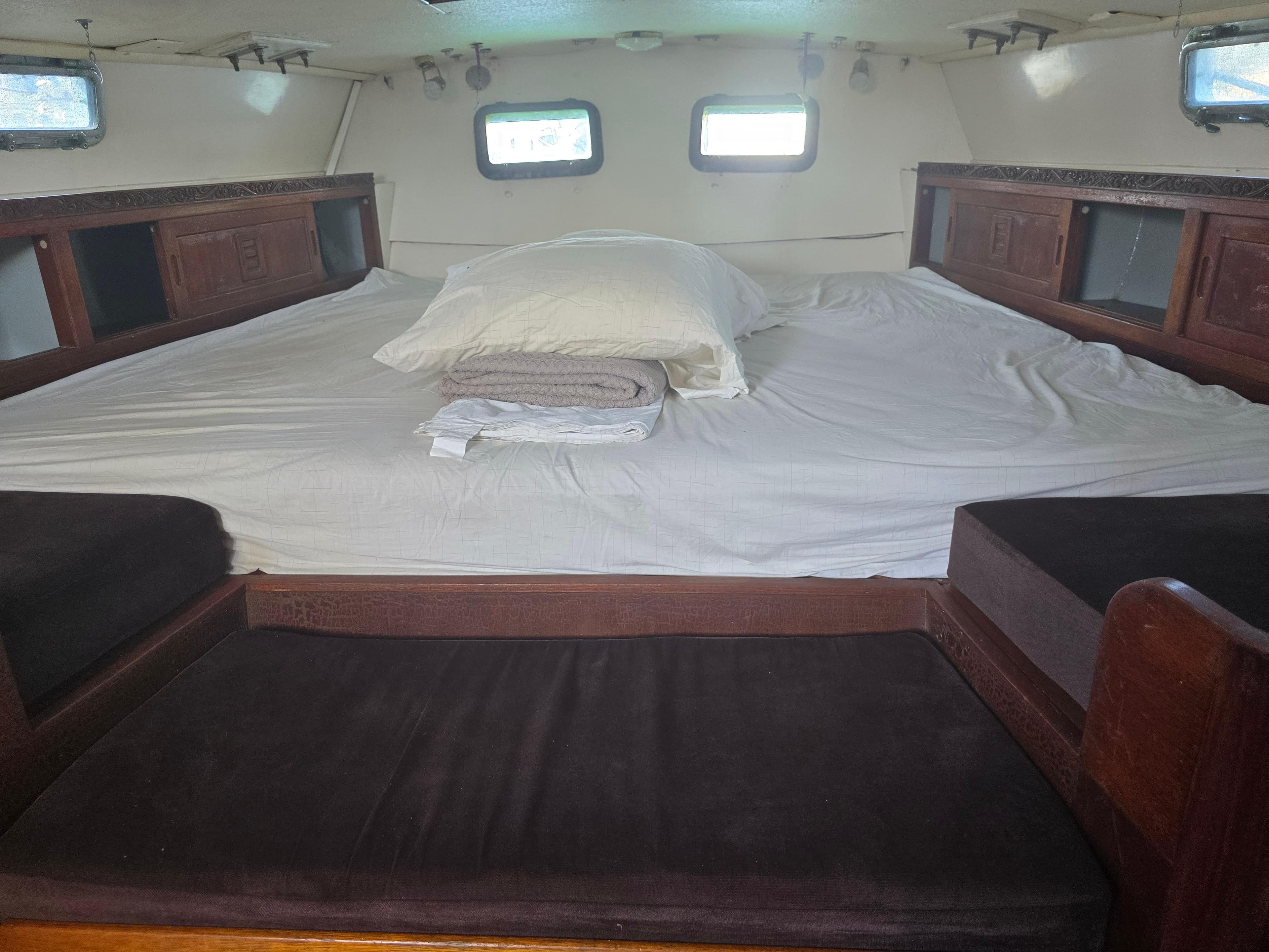 Cozy cabin interior of a 1978 Herreshoff 50 sailboat with a spacious bed and wooden accents.
