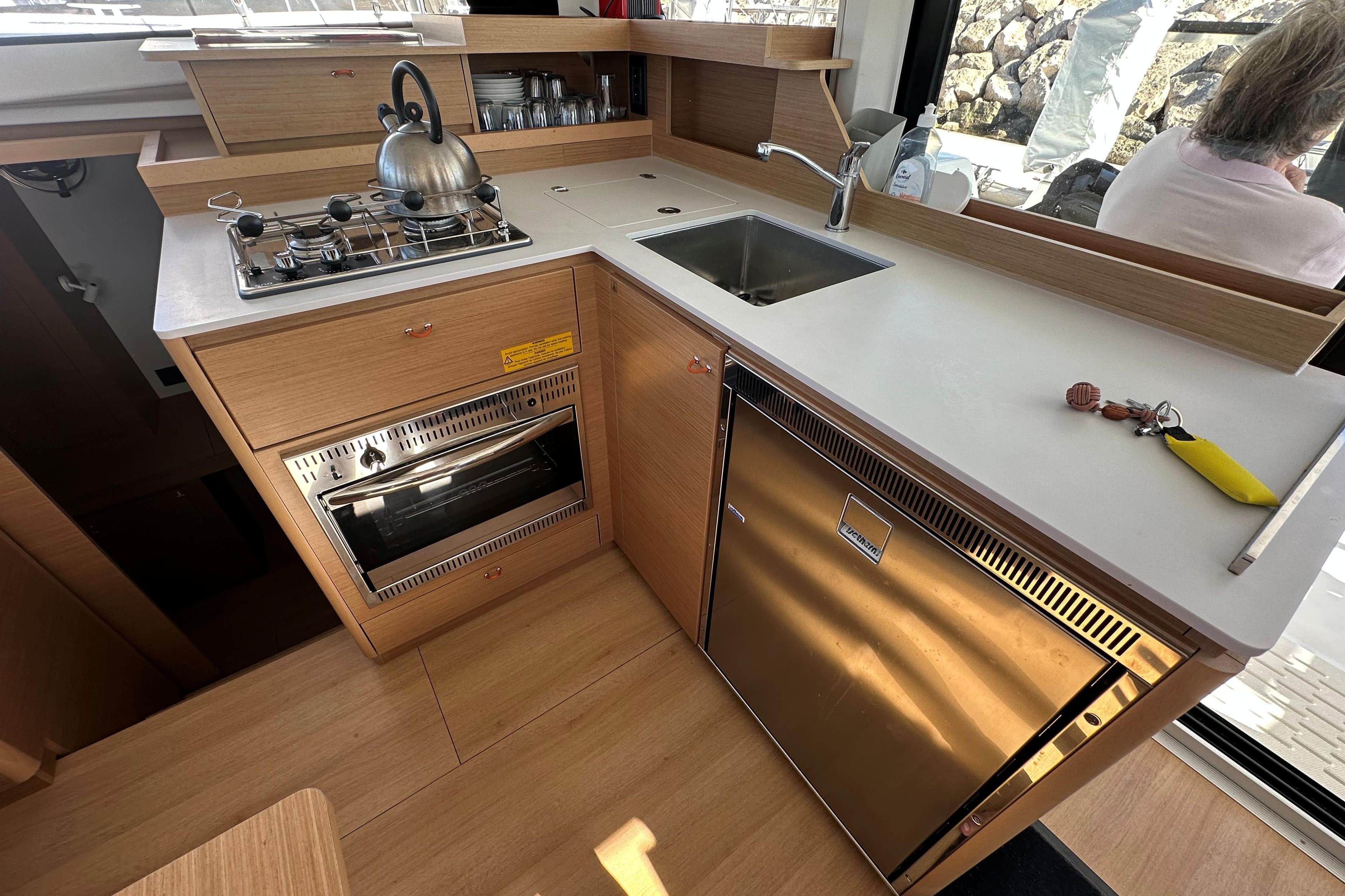 Modern kitchen in 2025 Excess 11 yacht with stove, sink, and fridge.