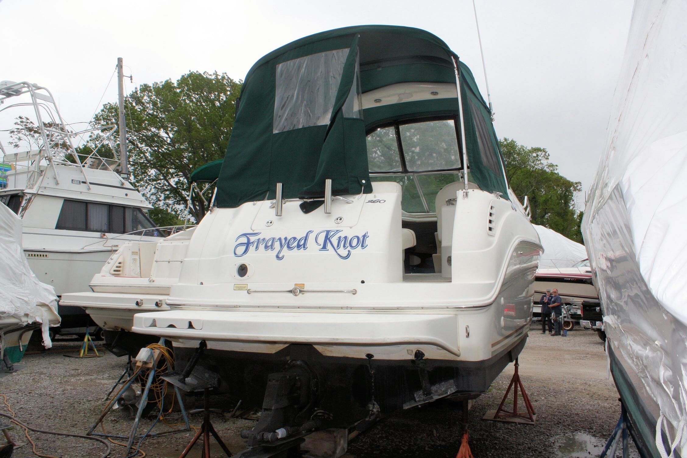 2003 Sea Ray 260 Sundancer boat with green canopy, named "Frayed Knot," on dry dock.