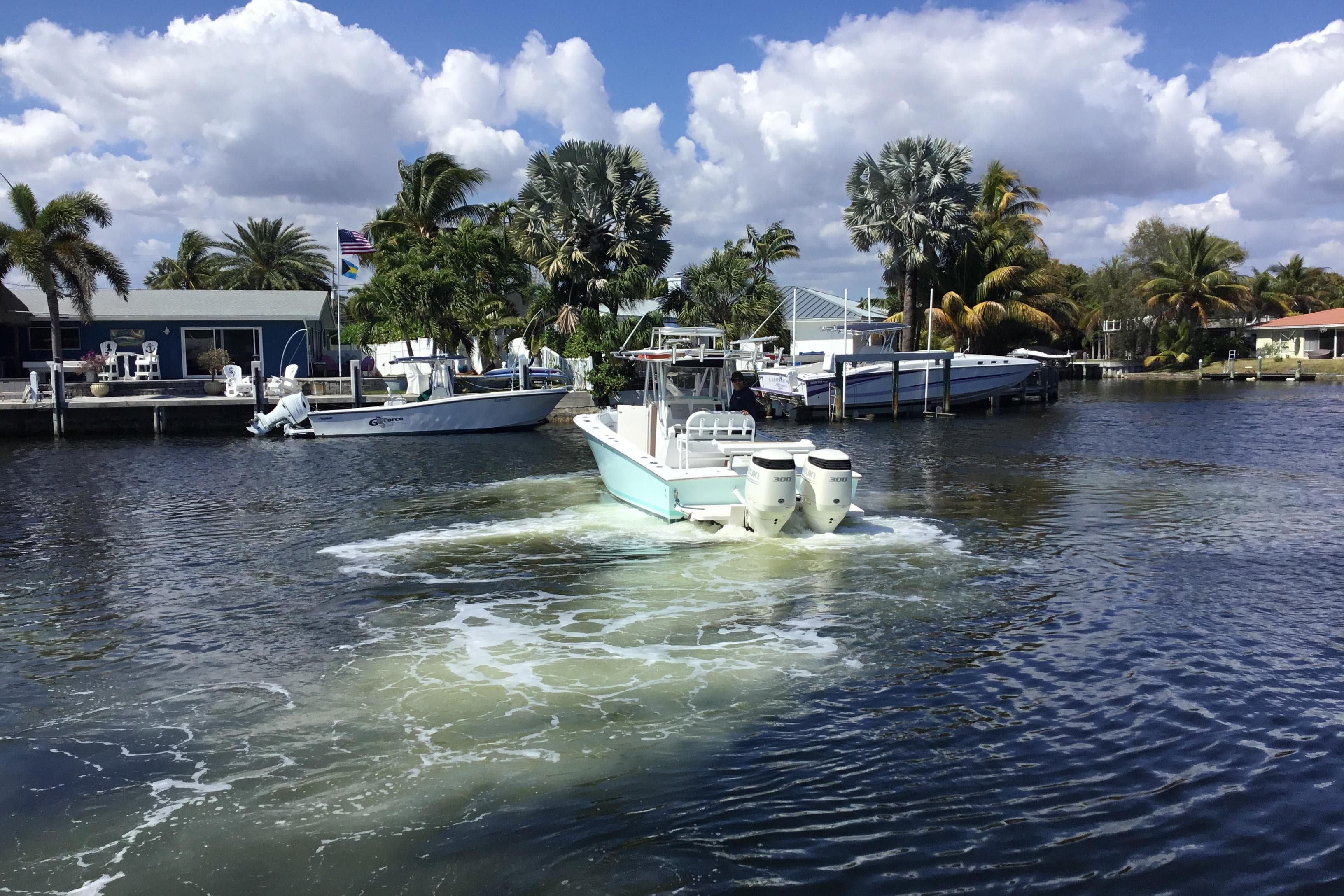 2000 Jupiter 31 Center Console boat navigating a scenic waterfront with palm trees.