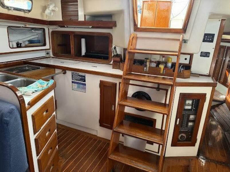 Interior of 1989 Catalina Morgan 440 sailboat, featuring wooden cabinetry and stairs.