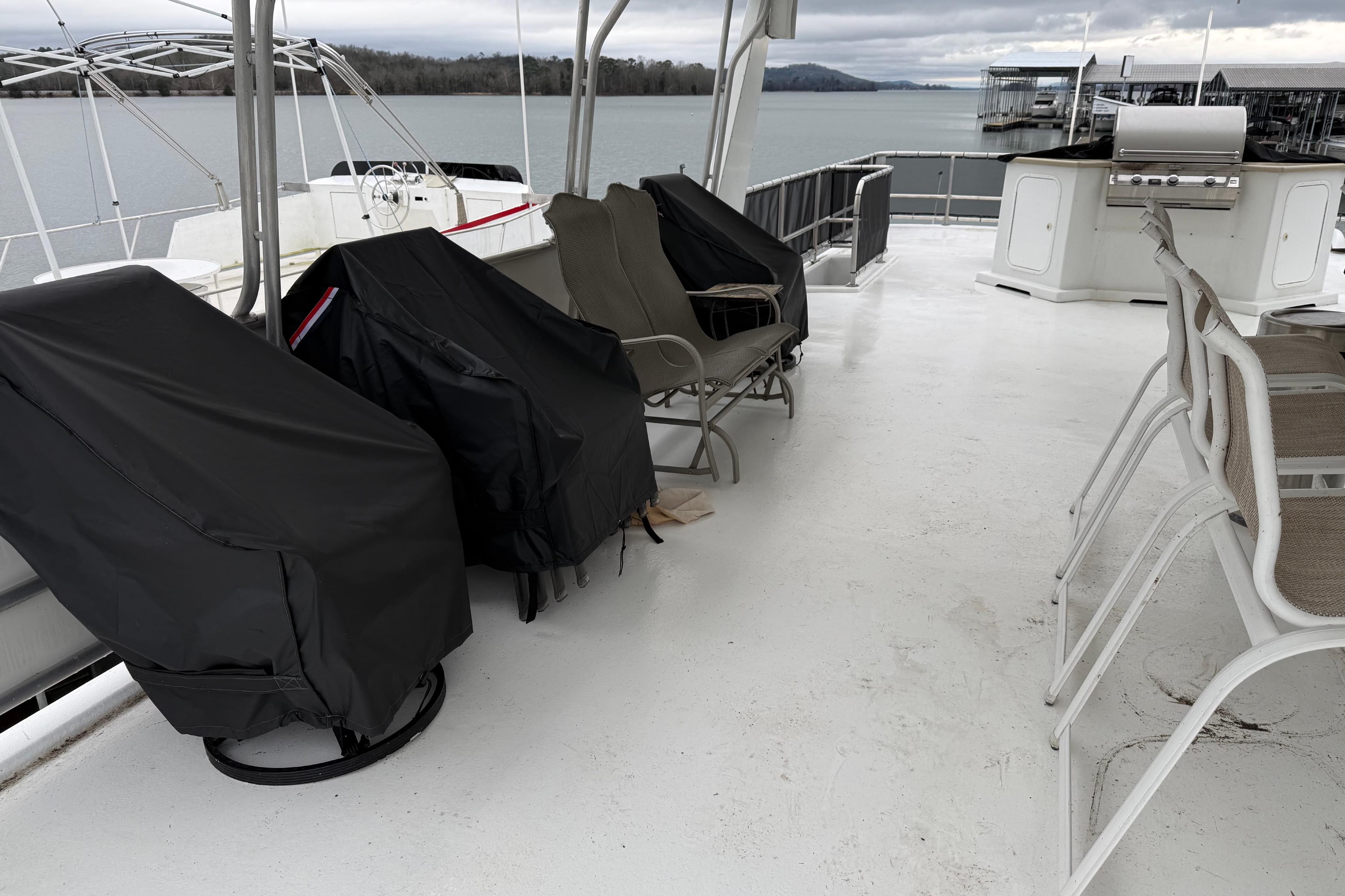 Upper deck of 2001 Sharpe 80 X 18 houseboat with covered chairs and grill.