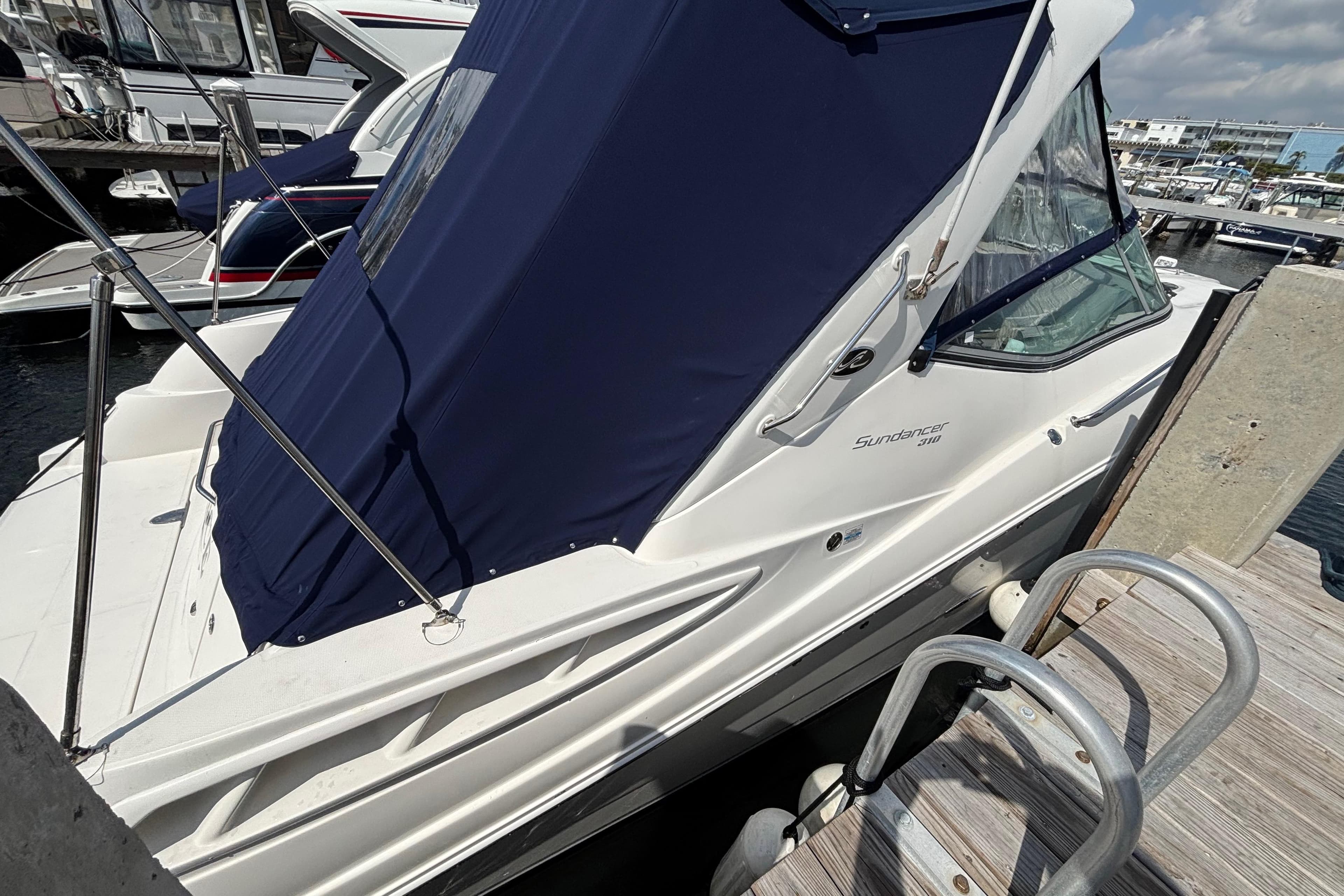 2009 Sea Ray Sundancer 310 docked, featuring blue canopy and sleek white design.