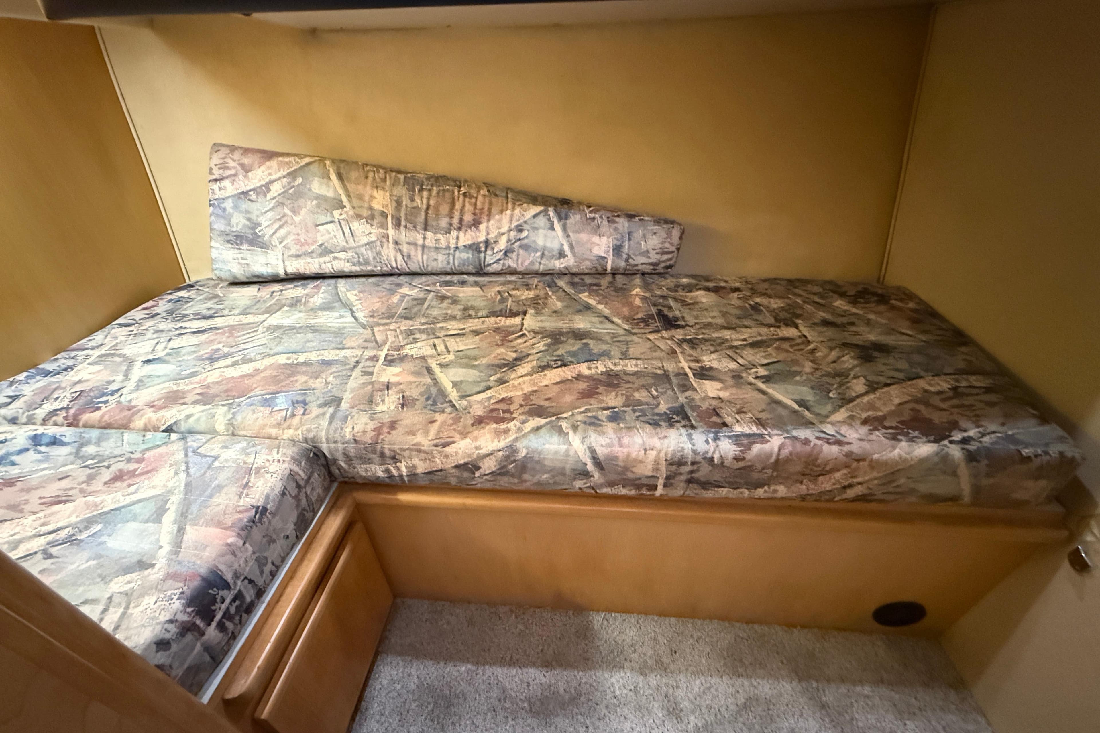1996 Carver 370 Voyager cabin bed with patterned upholstery and wooden storage.