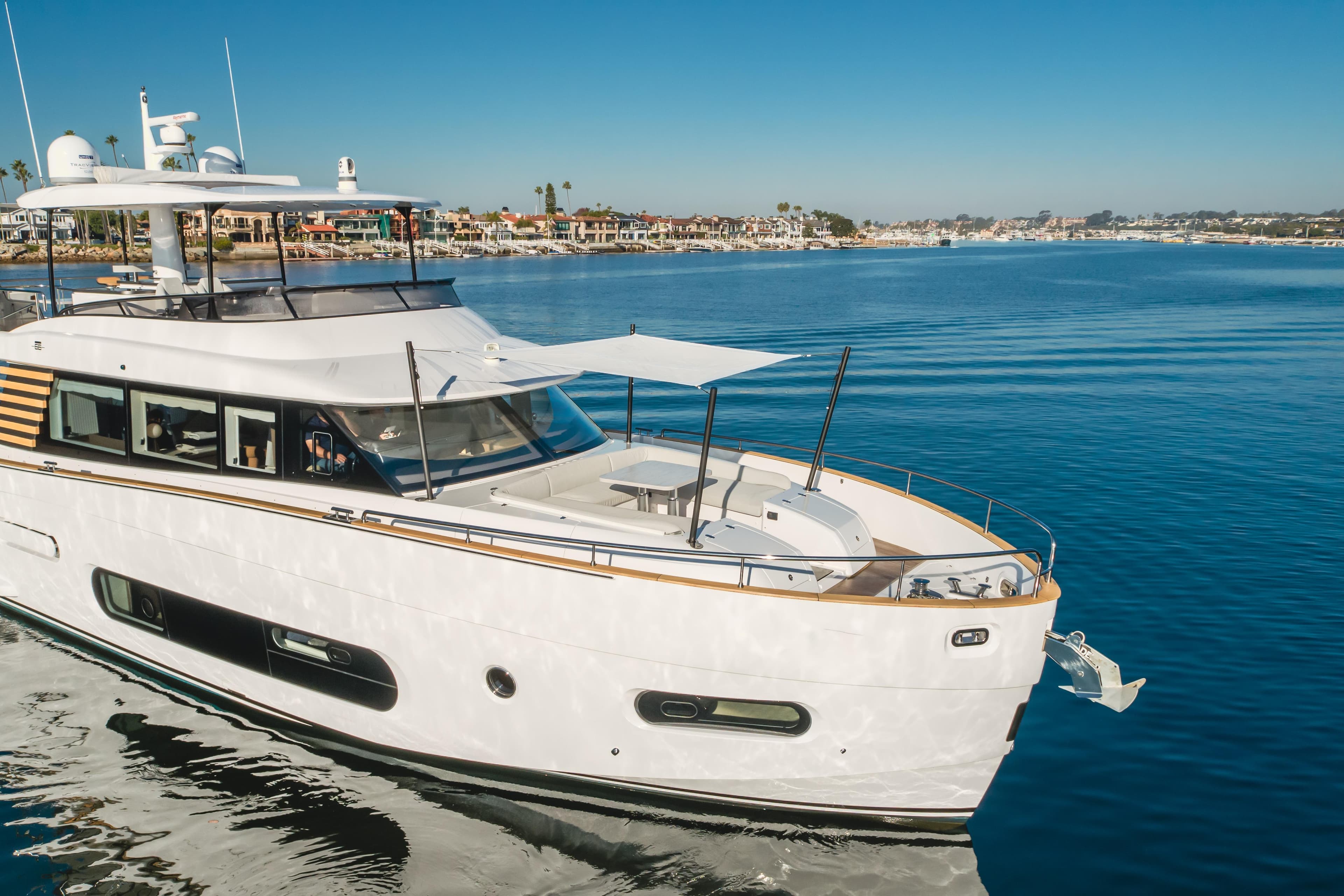 2023 Azimut Magellano 66 yacht cruising on calm waters near a coastal town.