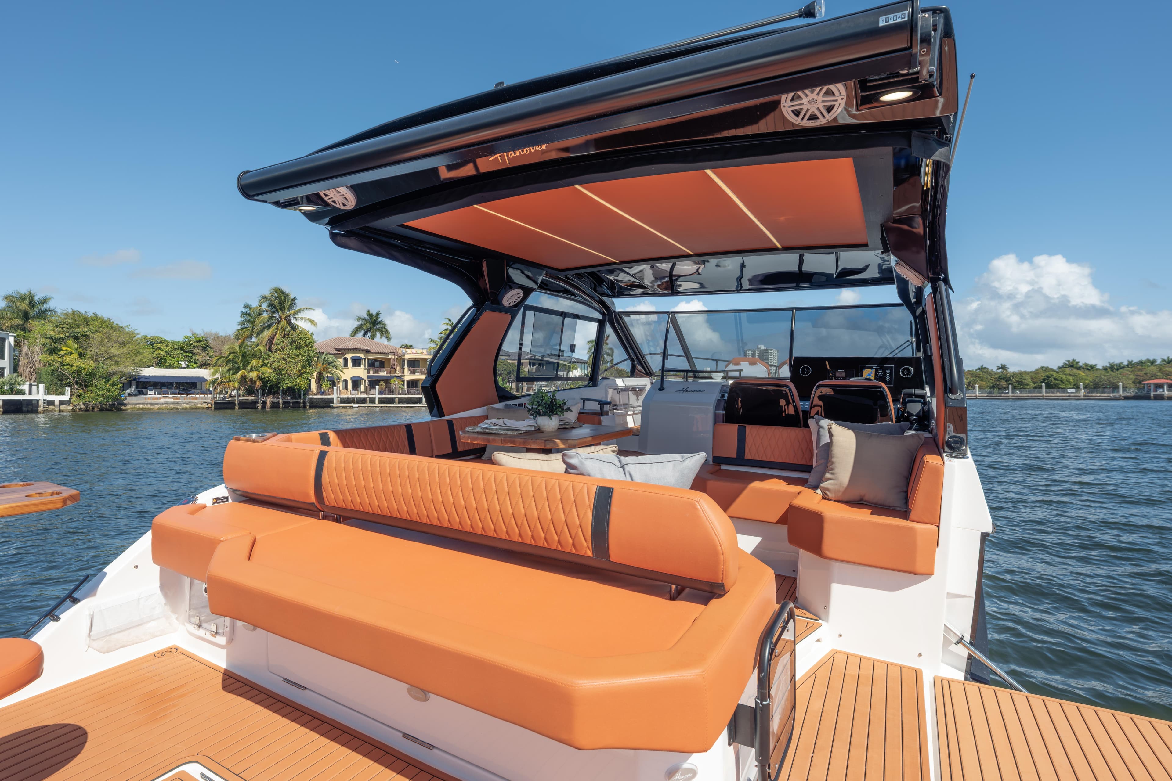 Luxurious 2026 Hanover 387 yacht interior with orange seating, cruising on a scenic waterway.