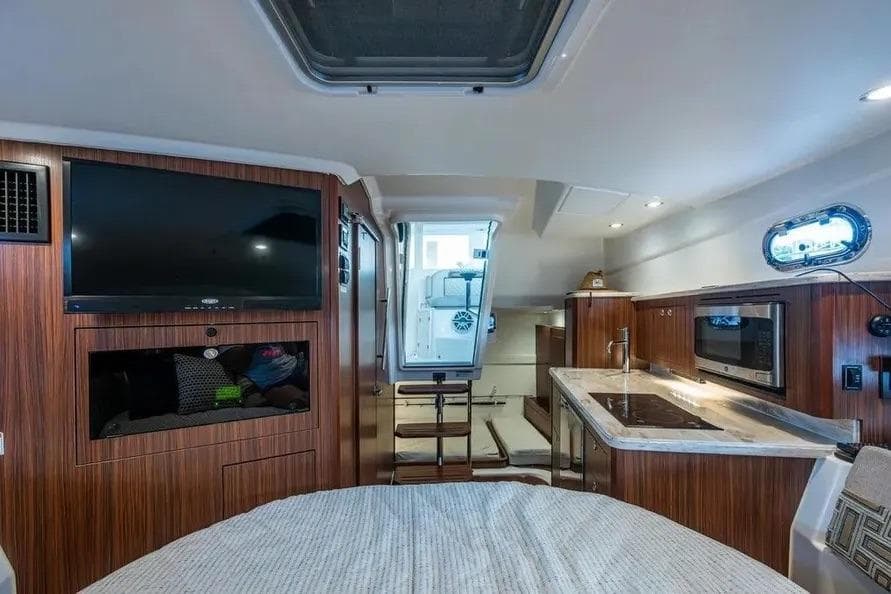 2023 Pursuit OS 355 Offshore cabin interior with kitchenette, TV, and modern amenities.
