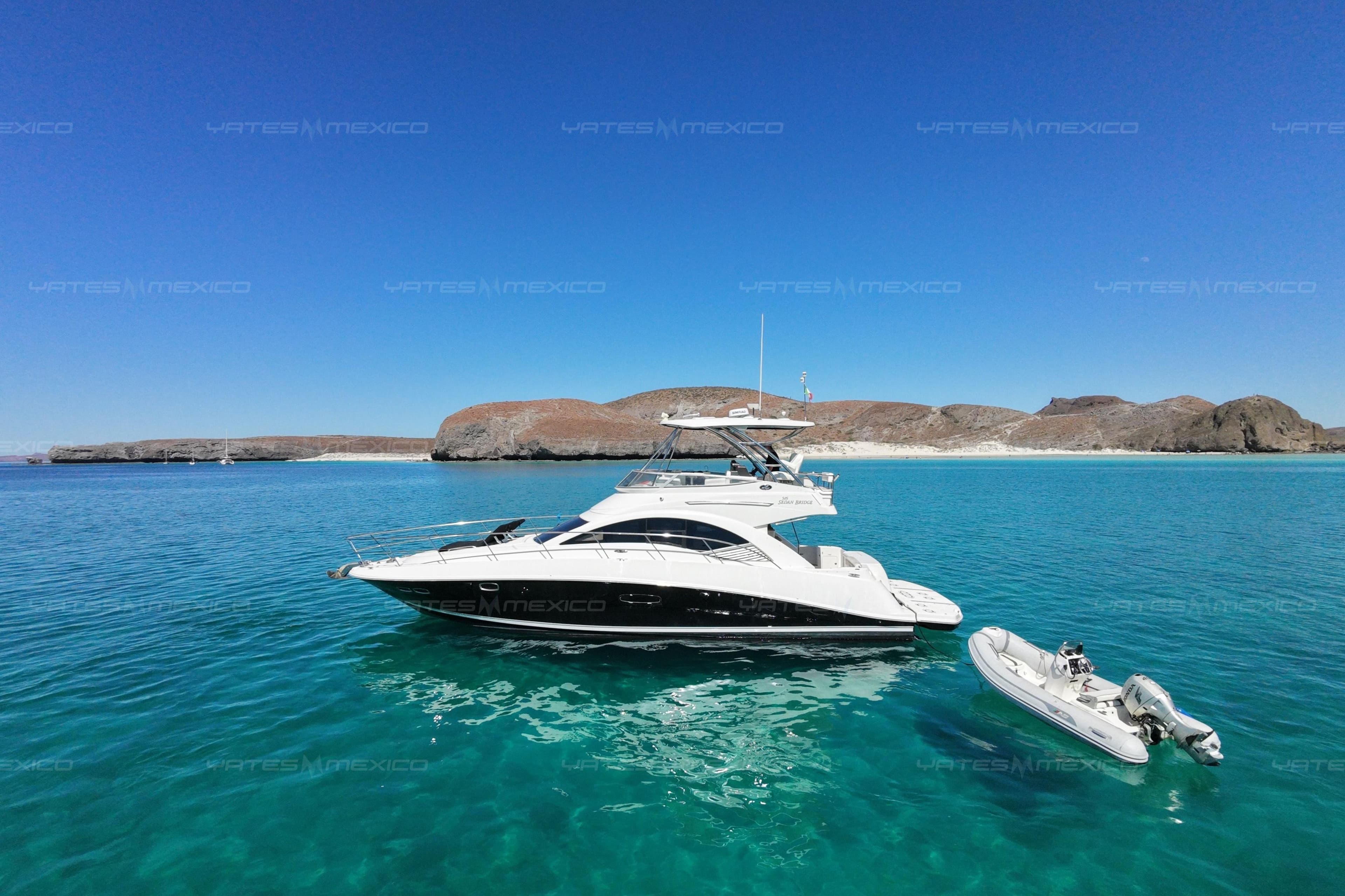 2008 Sea Ray 480 Sedan Bridge yacht on clear turquoise water near rocky coastline.