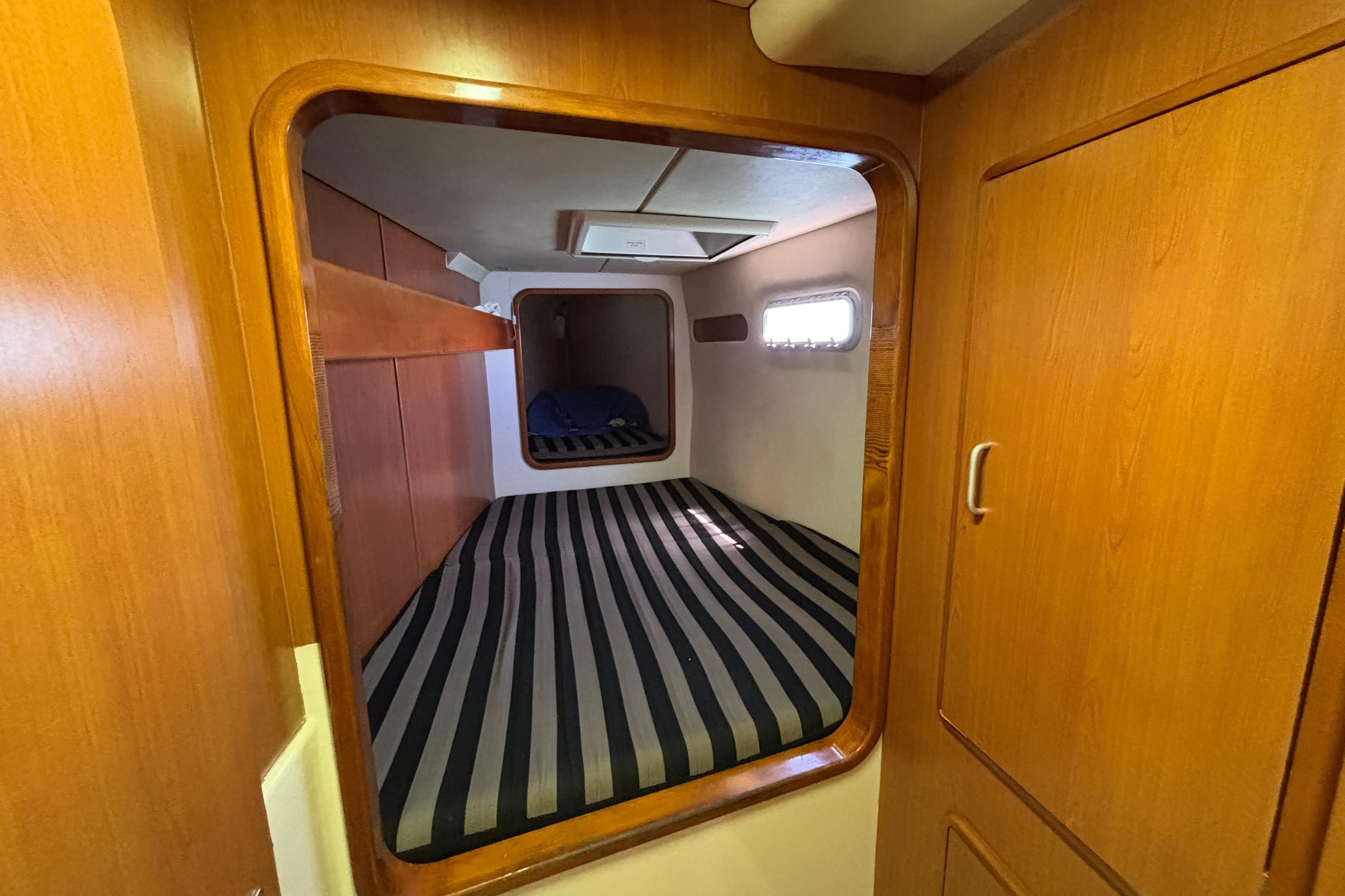 Cozy cabin interior of 2007 Leopard 40 catamaran with striped bedding and wooden finish.