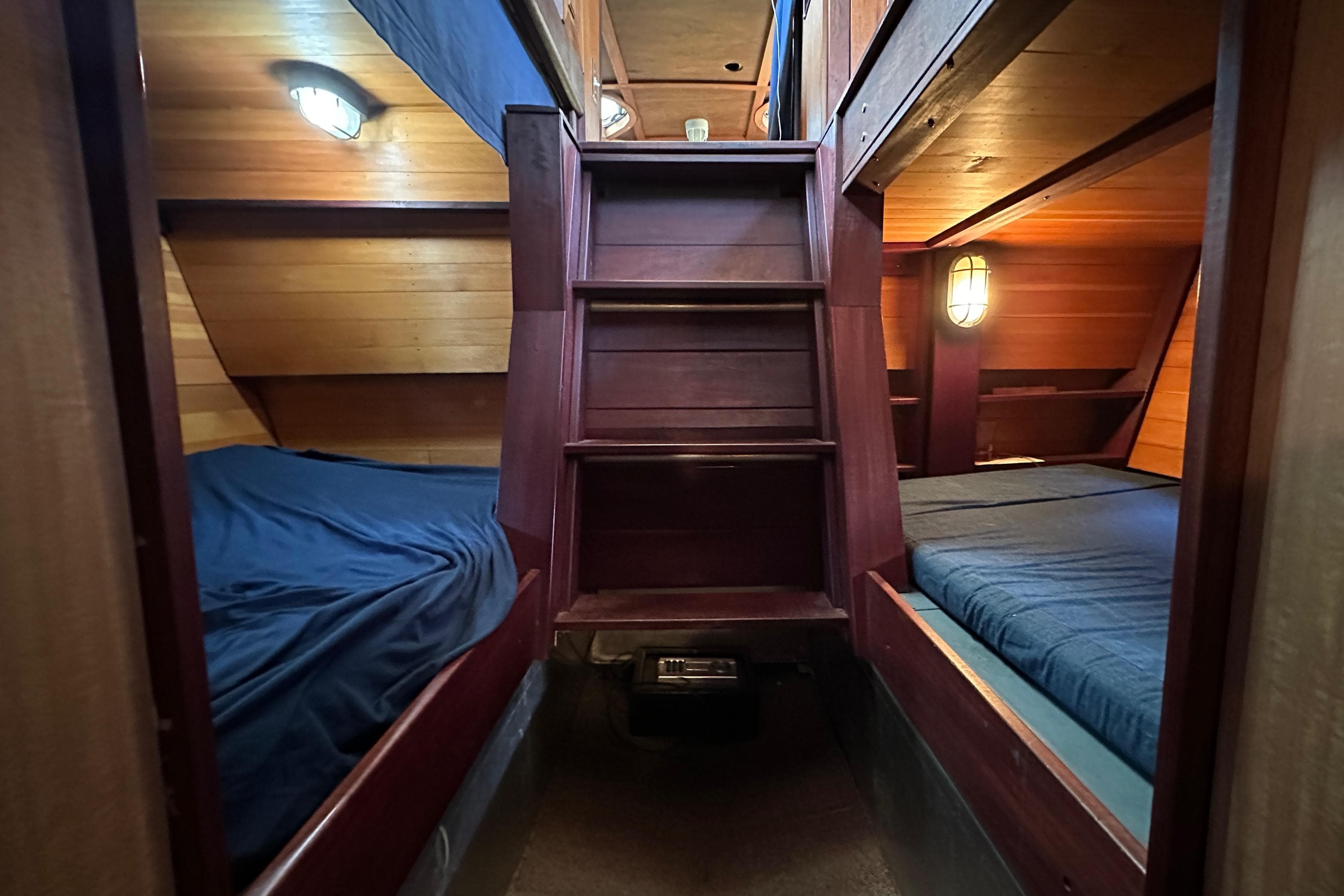 Cozy wooden cabin interior of 2002 Carlson Marine Trawler with twin beds and warm lighting.