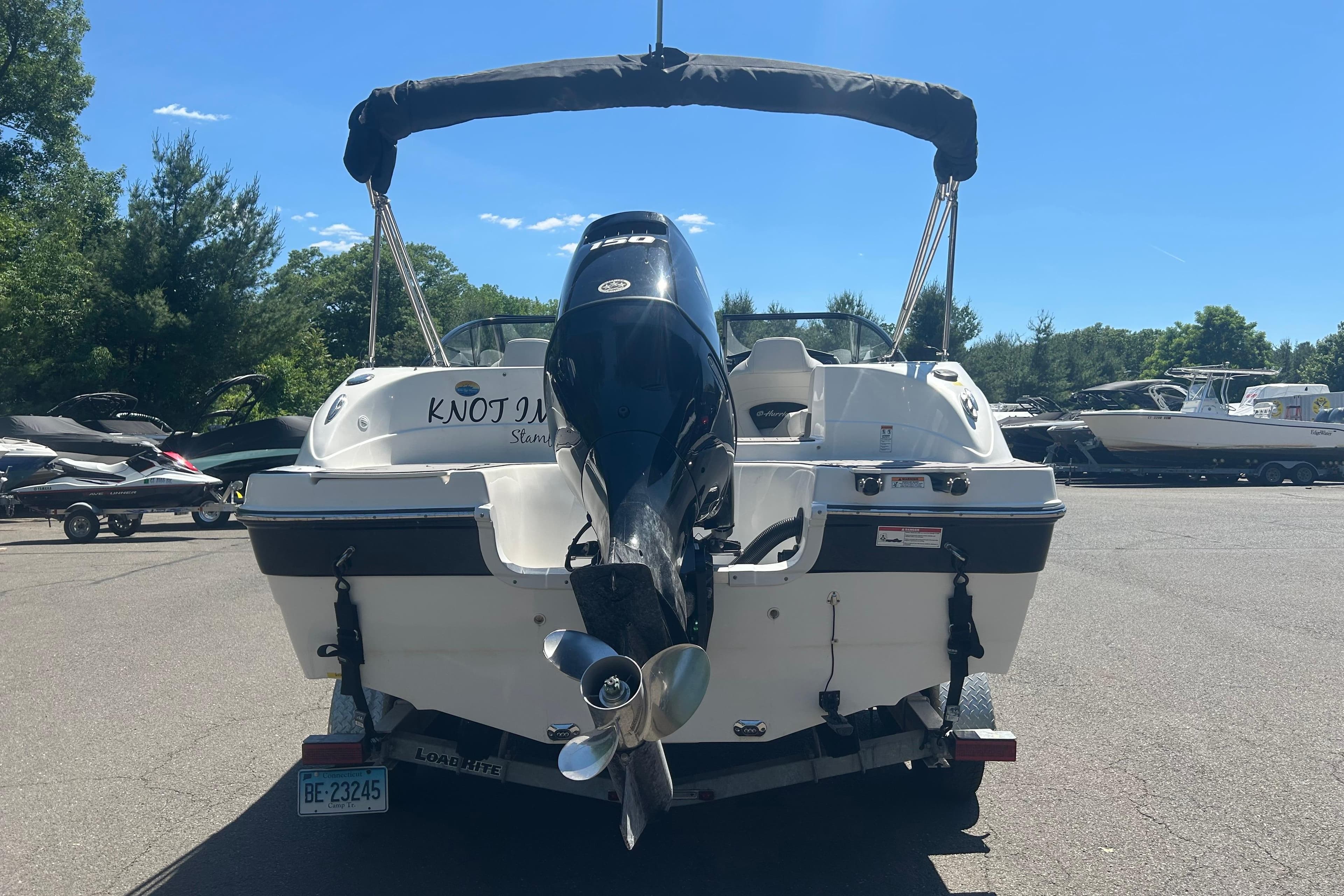 Rear view of a 2022 Godfrey sd217 boat on a trailer in a sunny parking lot.