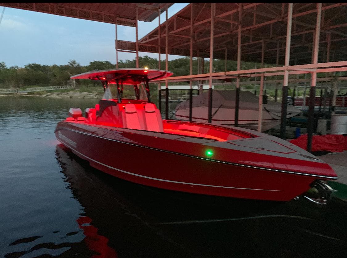 Red 2019 Statement 350 Open boat docked under a canopy at dusk.
