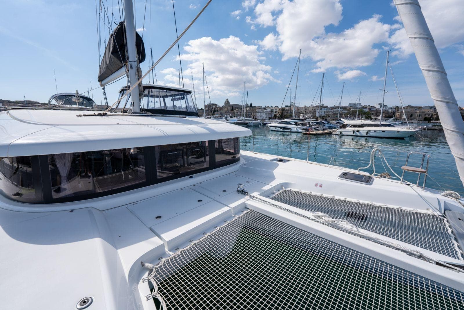 Modern Lagoon catamaran docked in marina, 2026 model, with clear blue sky and water.