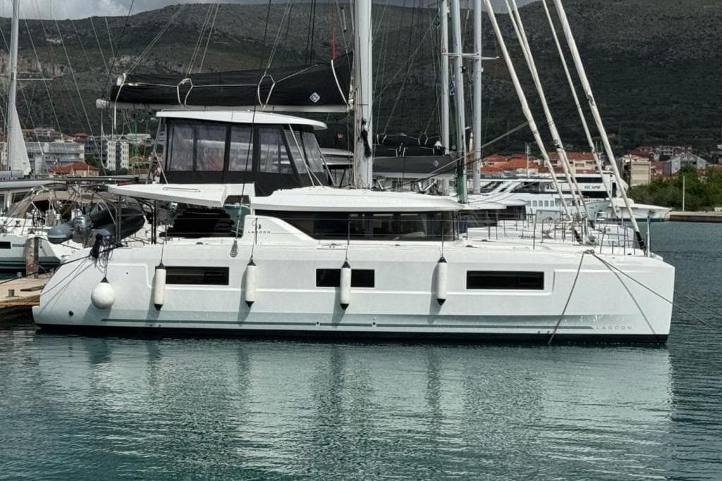 2020 Lagoon 46 catamaran docked in a marina, surrounded by water and other boats.