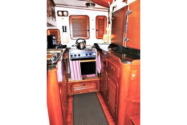 1982 Ta Shing Mason 63 yacht kitchen with wooden cabinetry and compact stove.