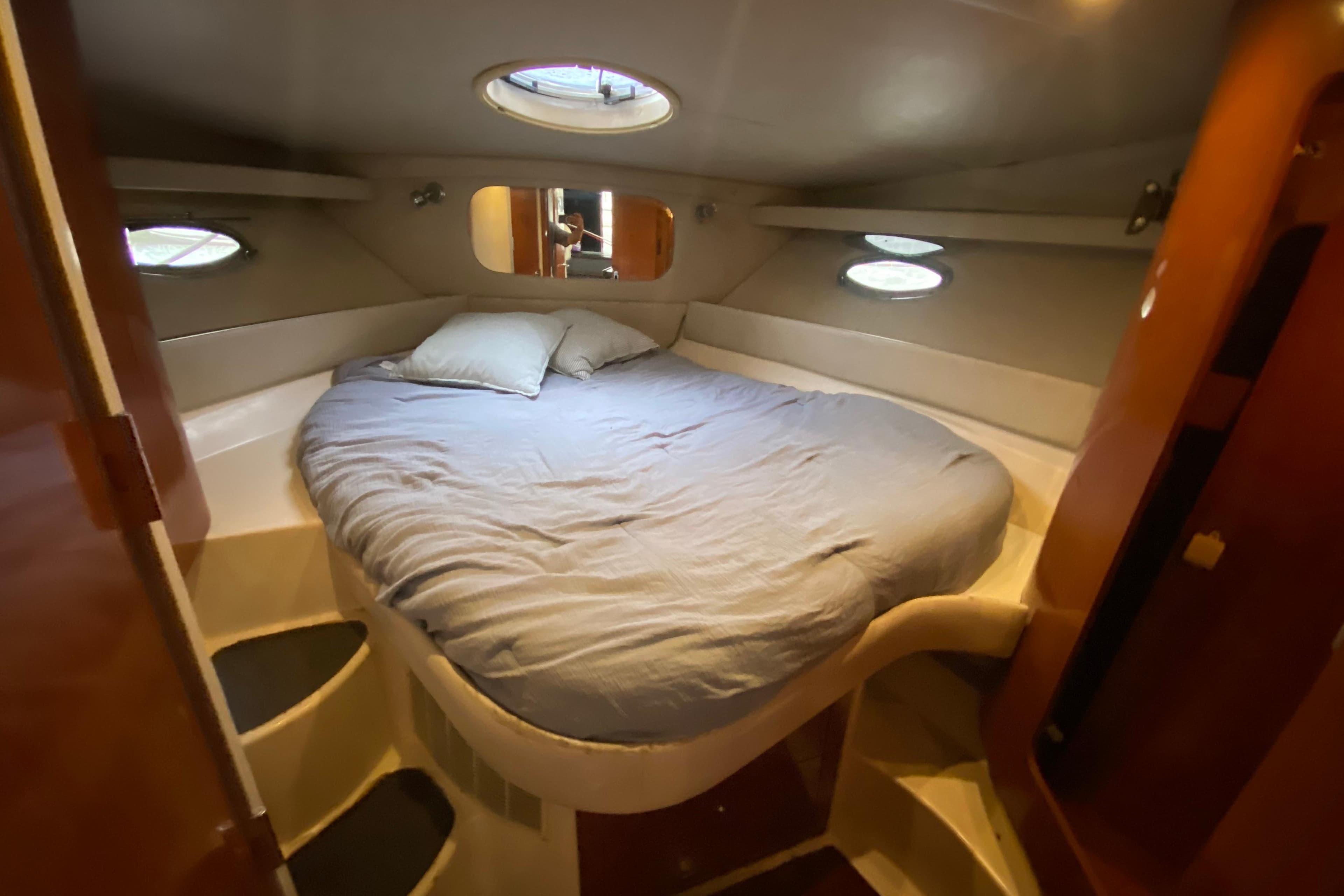Cozy cabin interior of 2006 Regal Commodore 3880 yacht with circular bed and portholes.