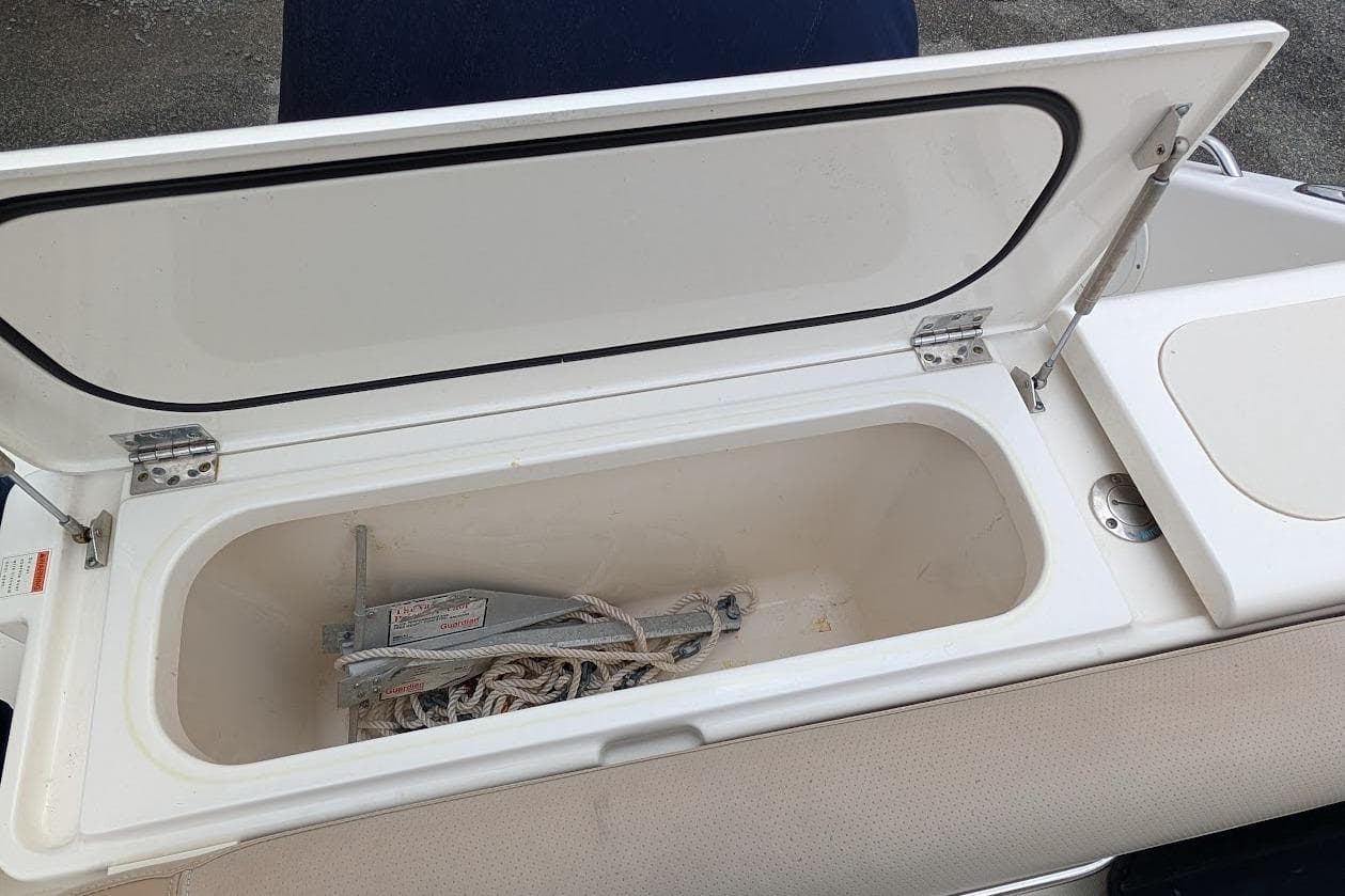 Open storage compartment on 2011 Pursuit DC 265 Dual Console boat, containing anchor and rope.
