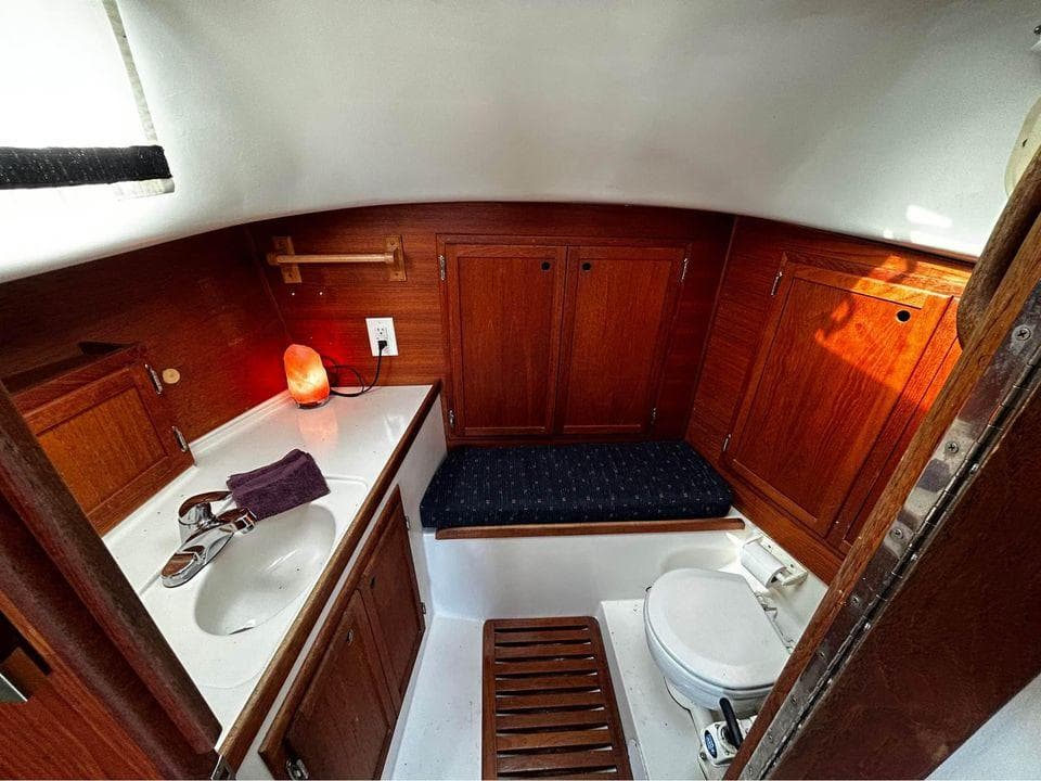 1980 Bayfield Sloop bathroom with wooden cabinets, sink, and toilet.