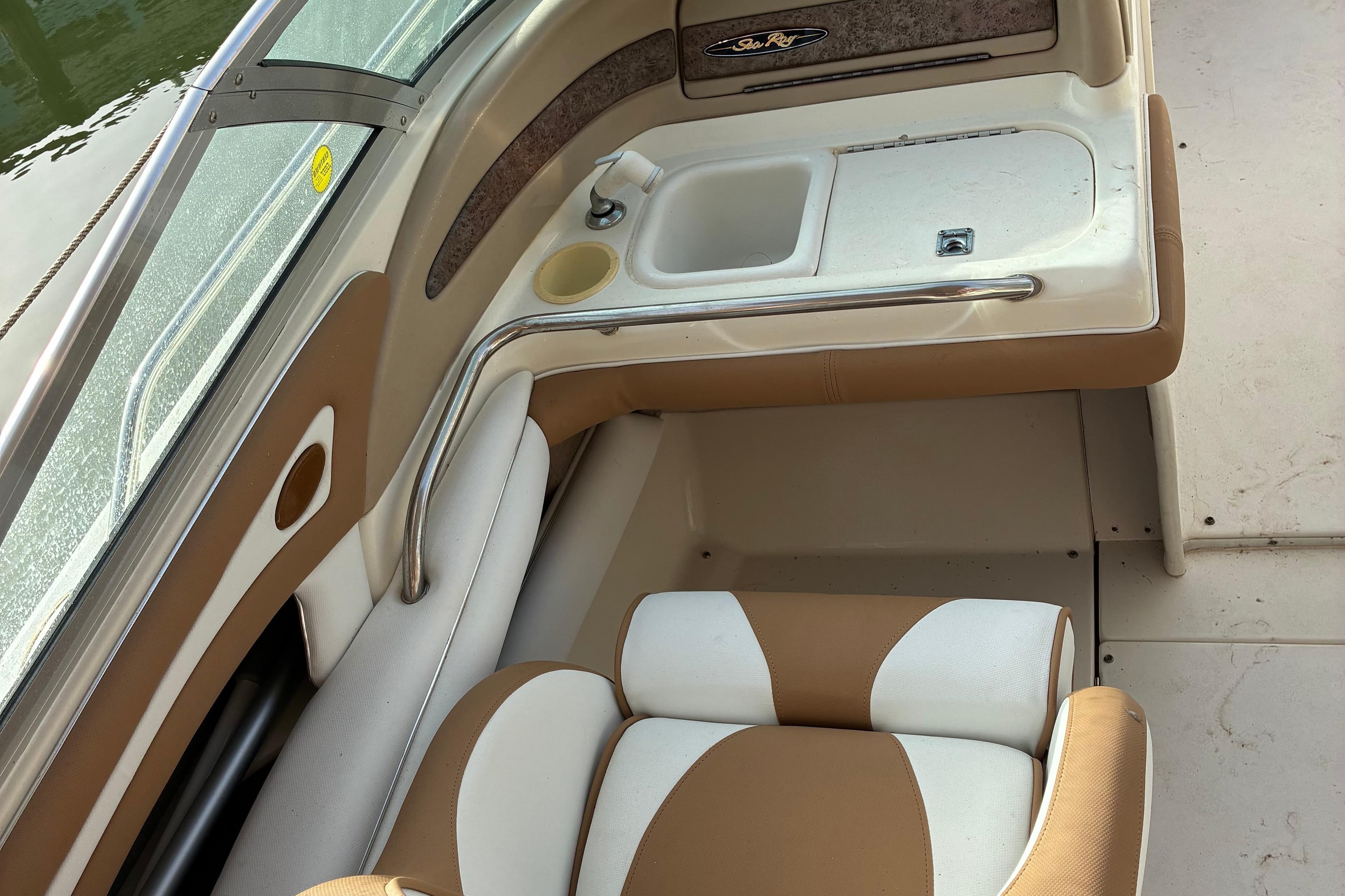 1998 Sea Ray 230 Sundeck interior with seating and sink, featuring tan and white upholstery.