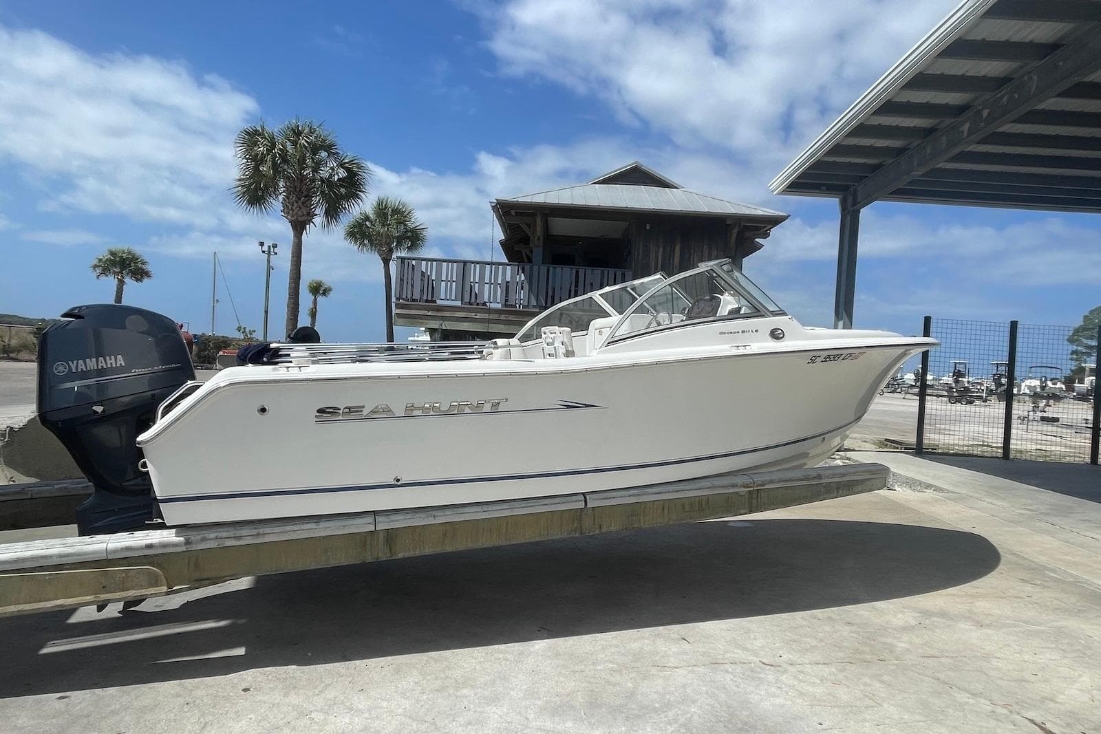 2013 Sea Hunt Escape 211 LE boat on trailer with Yamaha engine, under clear blue sky.