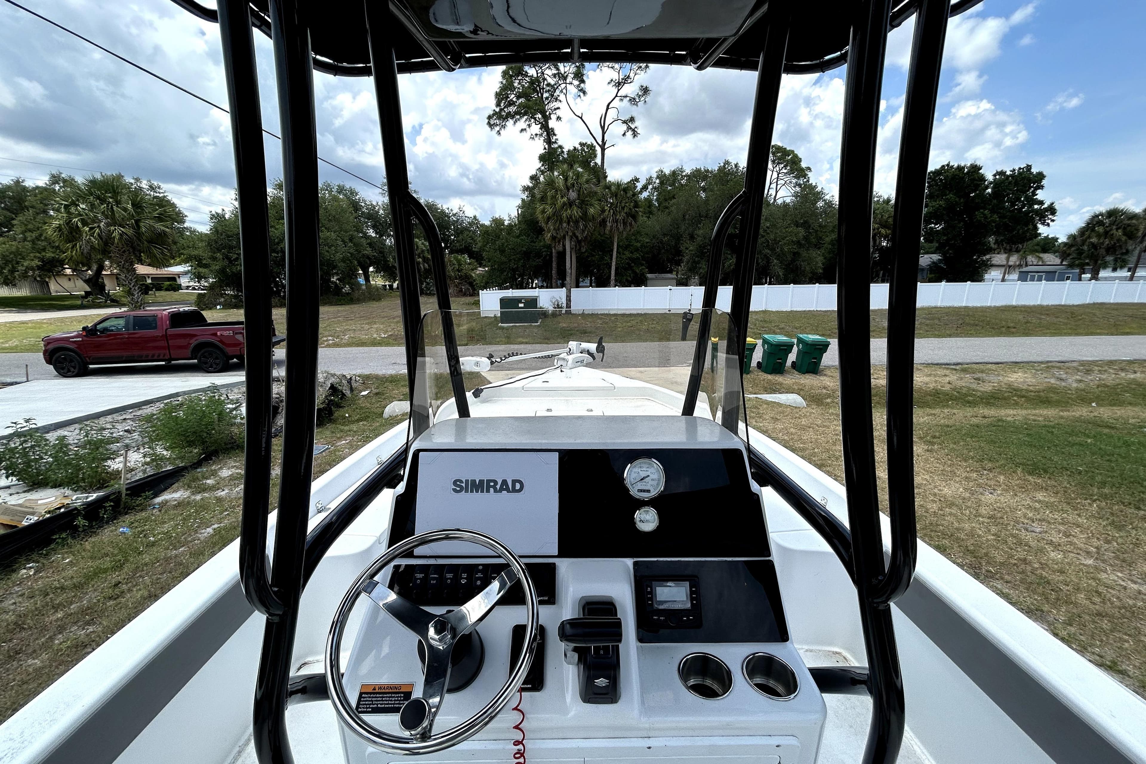 2025 Savannah 210X boat dashboard with steering wheel and Simrad display, parked outdoors.