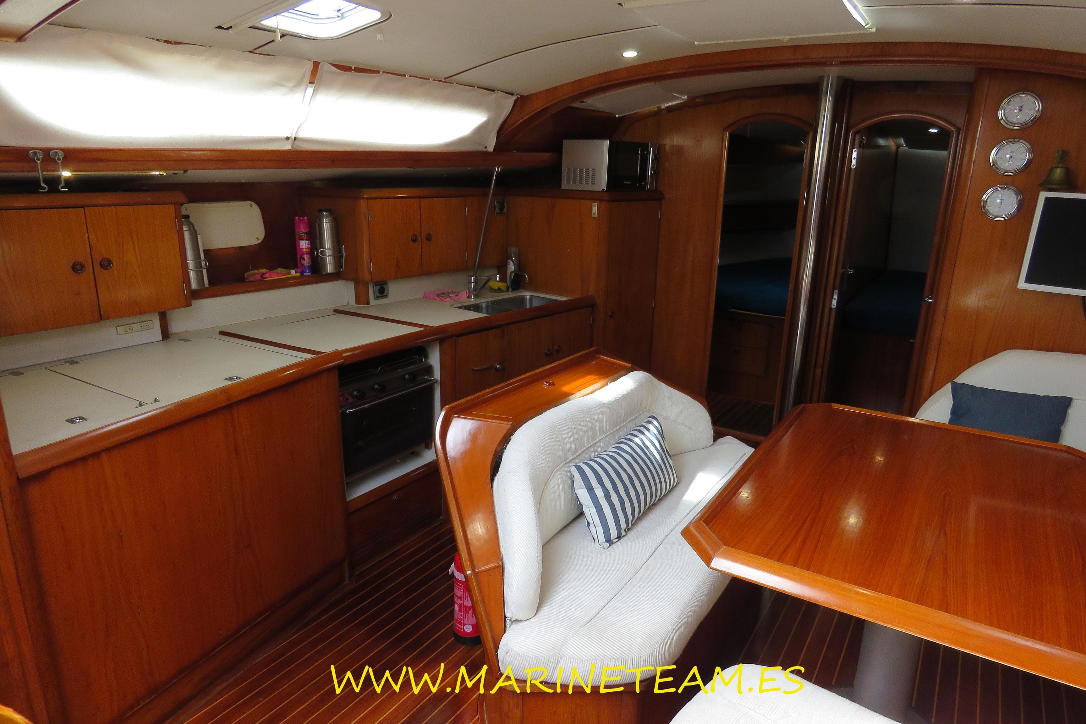 Interior of 1995 Jeanneau Sun Odyssey 45.1 yacht with wooden cabinetry and dining area.