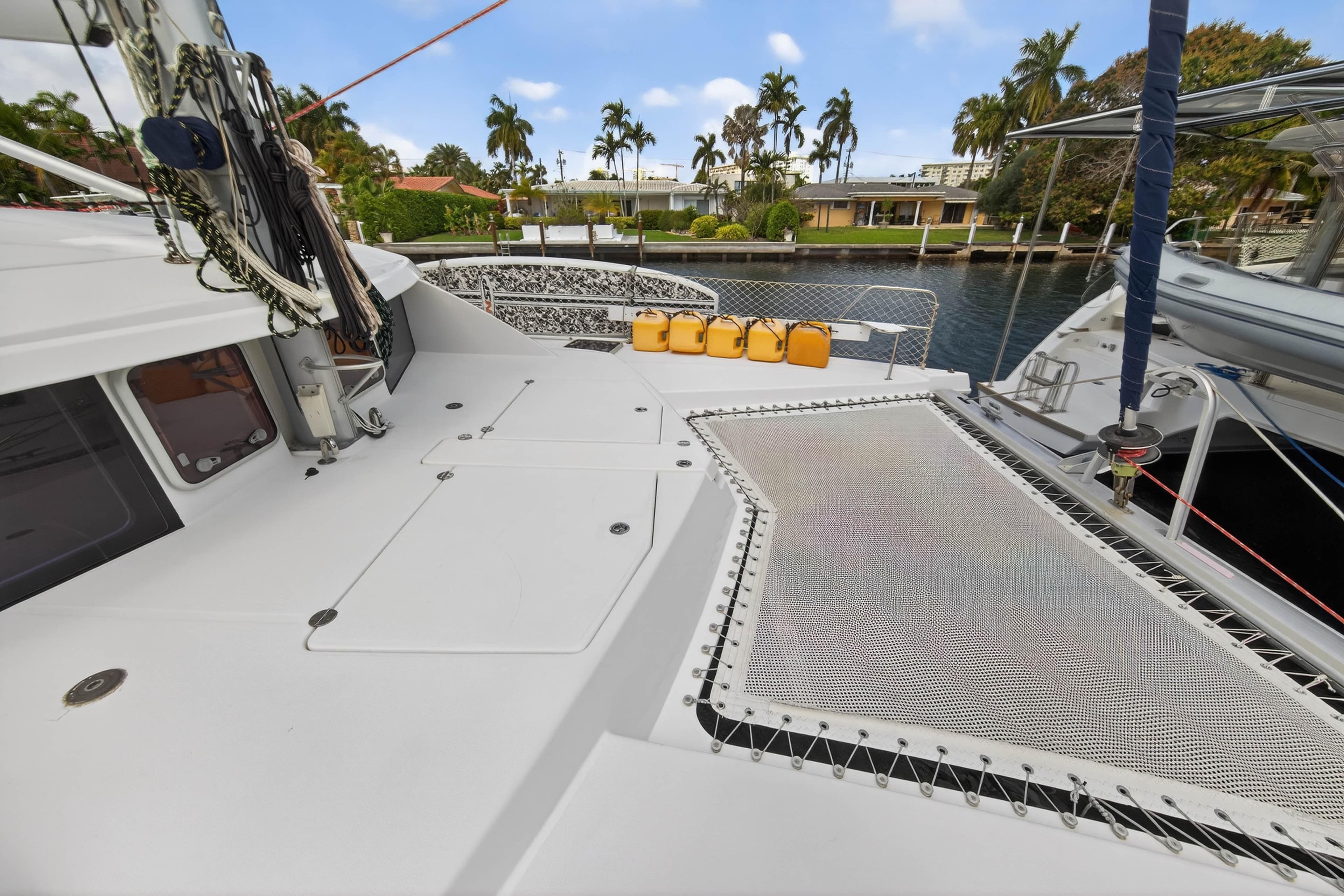 2012 Leopard 39 catamaran deck with netting and yellow fuel containers, docked near palm trees.