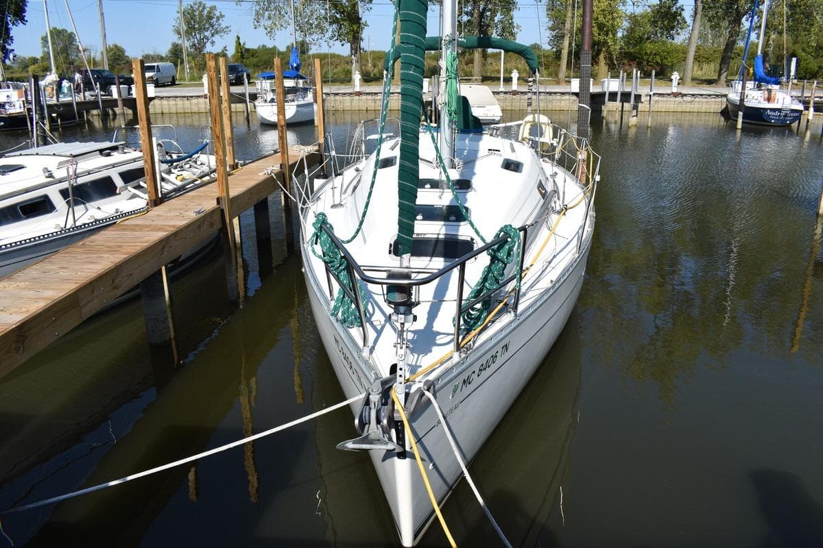 1996 Beneteau Oceanis 321 sailboat docked in a marina, surrounded by calm water.