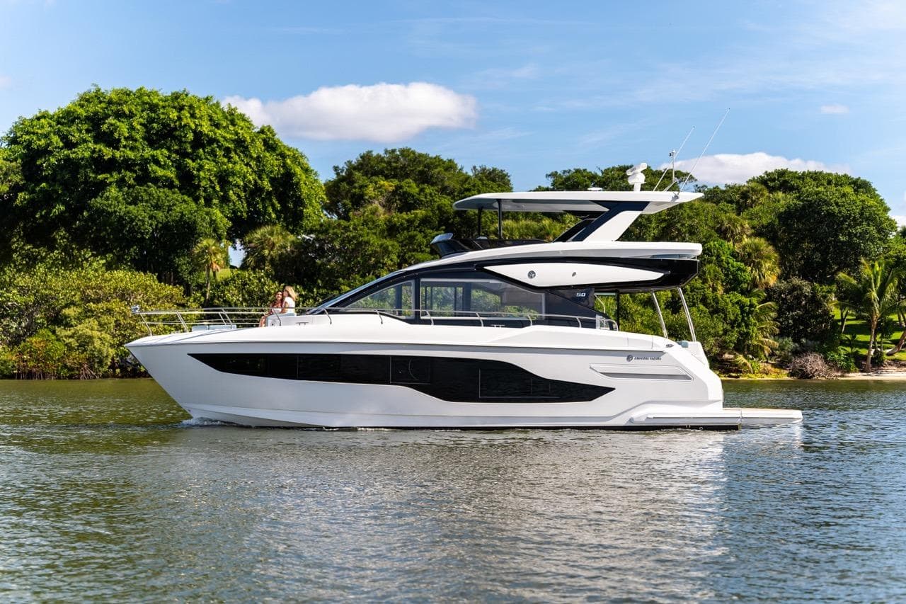 2026 Cruisers Yachts 50 Fly luxury yacht cruising on a serene lake.
